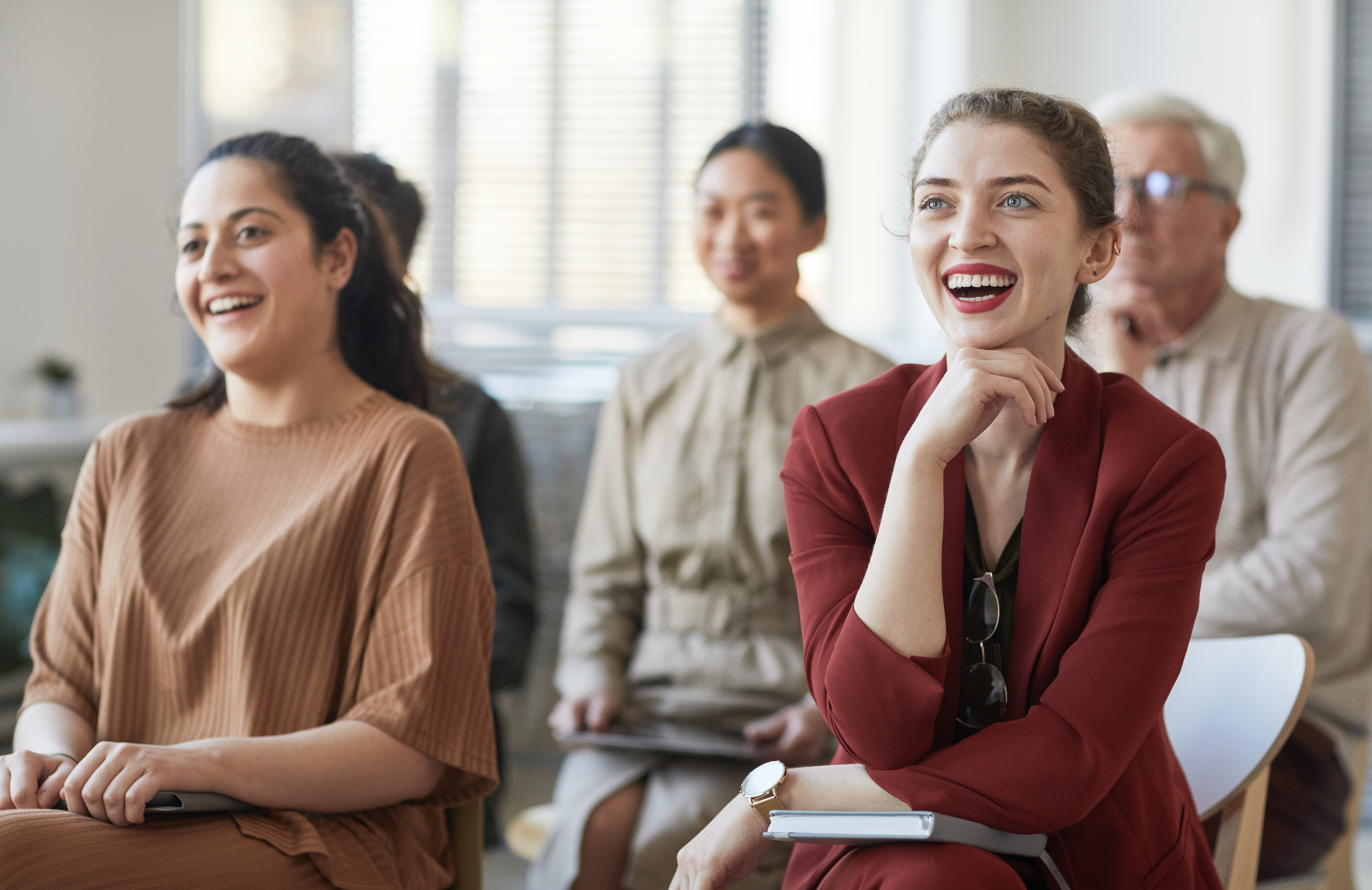 Diverse group of people smiling and engaged in a seminar or workshop.