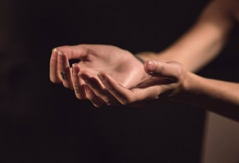 Close-up of open hands with soft lighting against a dark background.