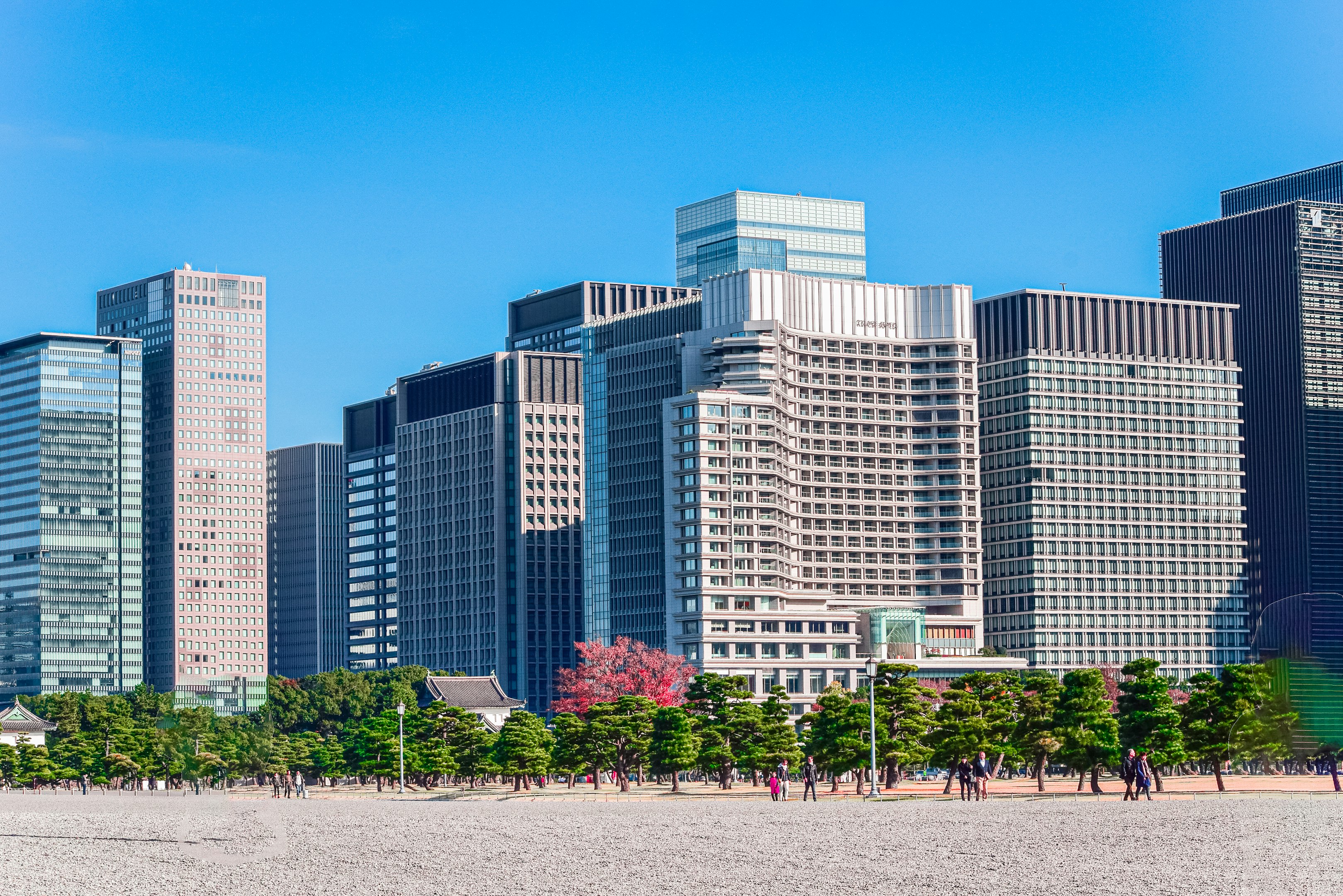 a group of people walking on a beach in front of tall buildings