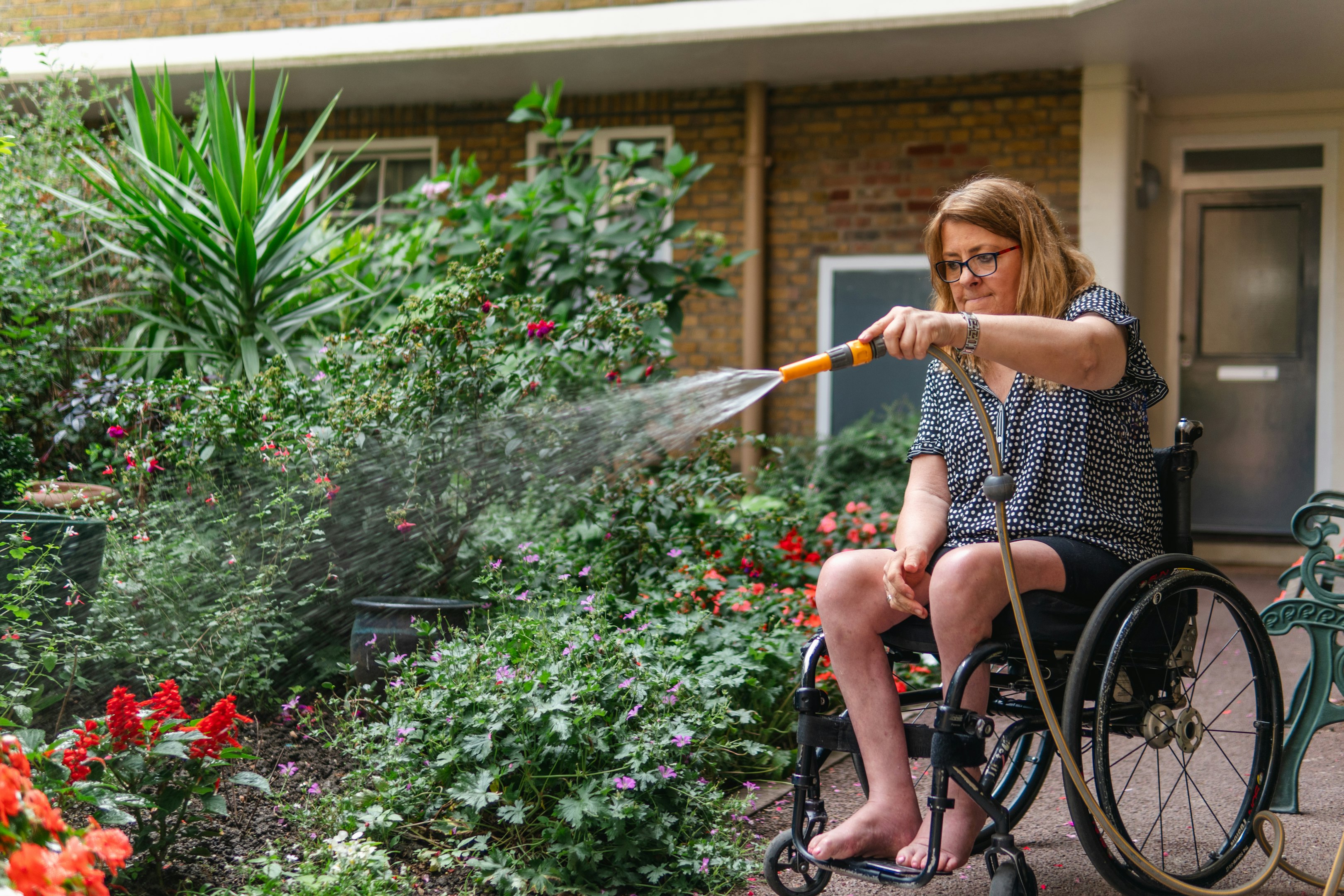Two colleagues in a modern office, one sitting in a wheelchair holding a tablet, interacting with a standing colleague. Two colleagues in a modern office, one sitting in a wheelchair holding a tablet, interacting with a standing colleague.