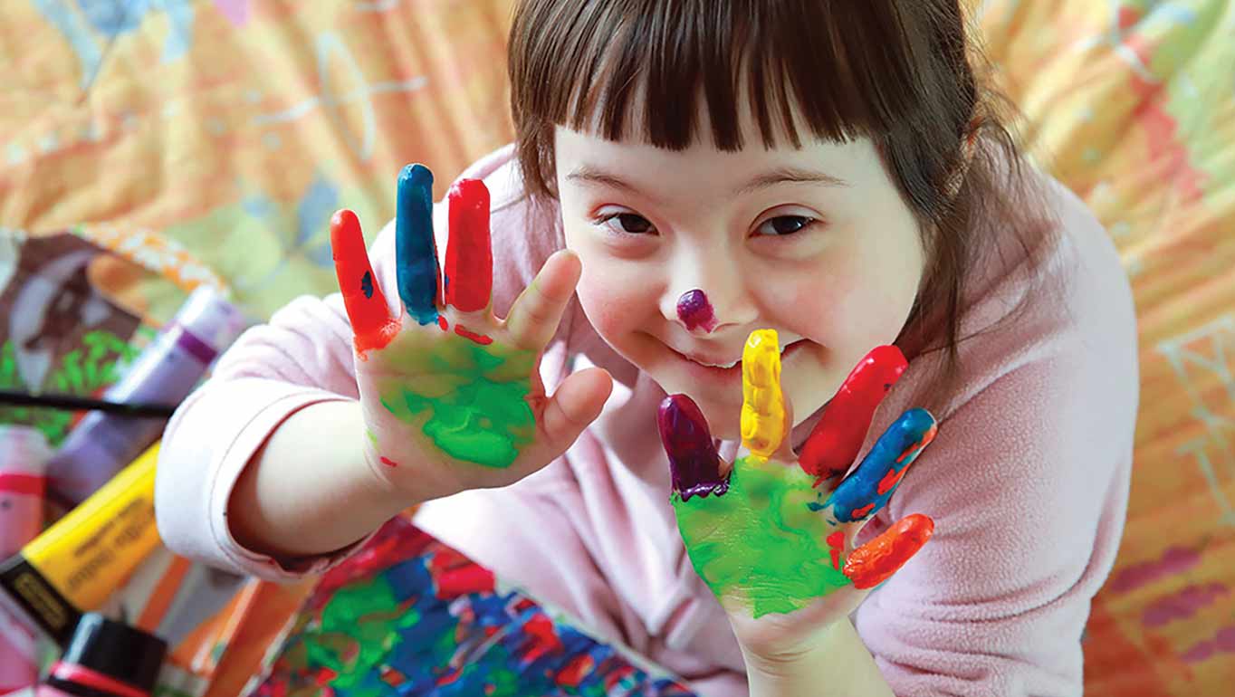 Close-up of a person writing on papers with a pen, wearing a blue shirt.