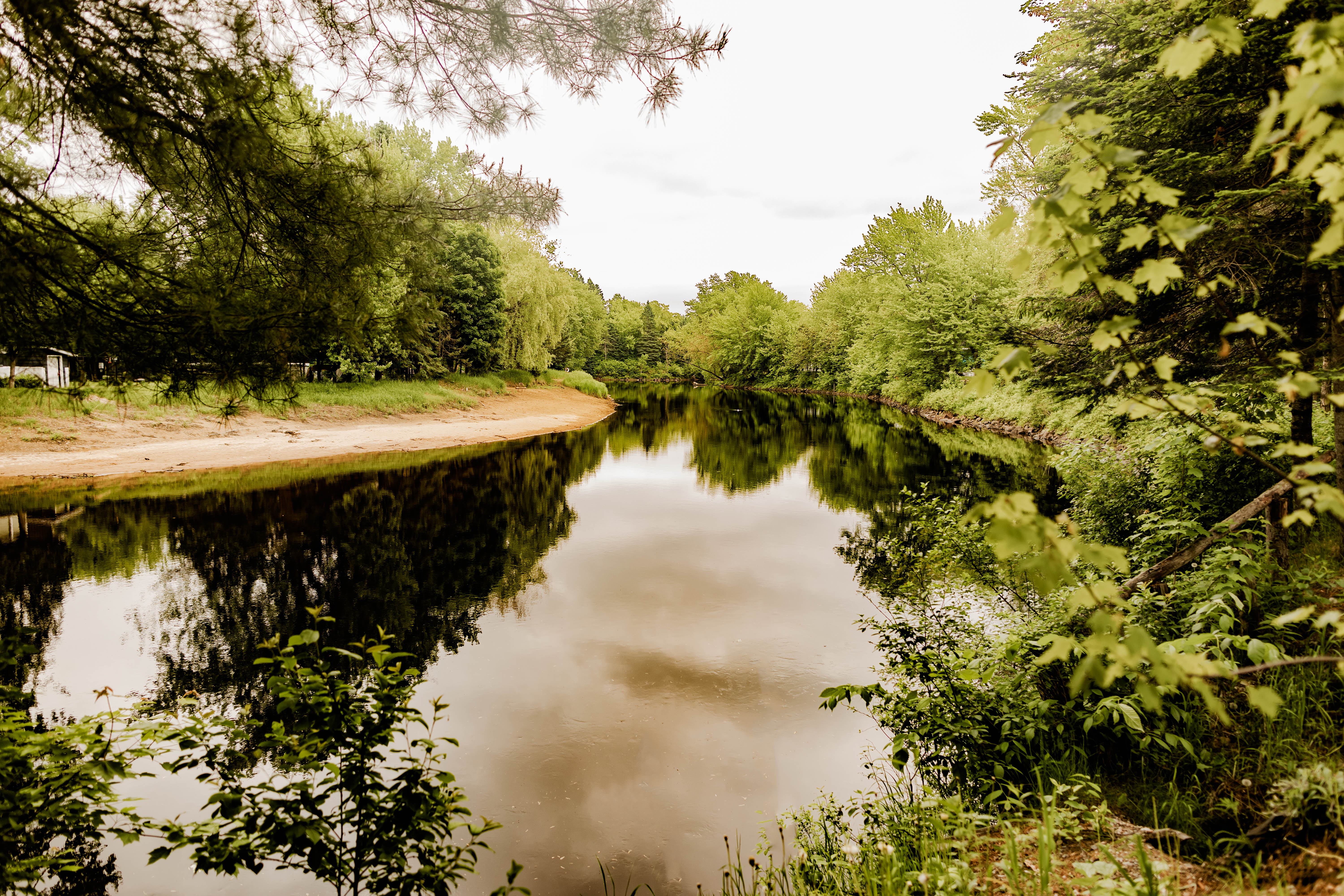 Canoë orange sur un lac calme entouré de montagnes et de forêt, ciel bleu et nuages.