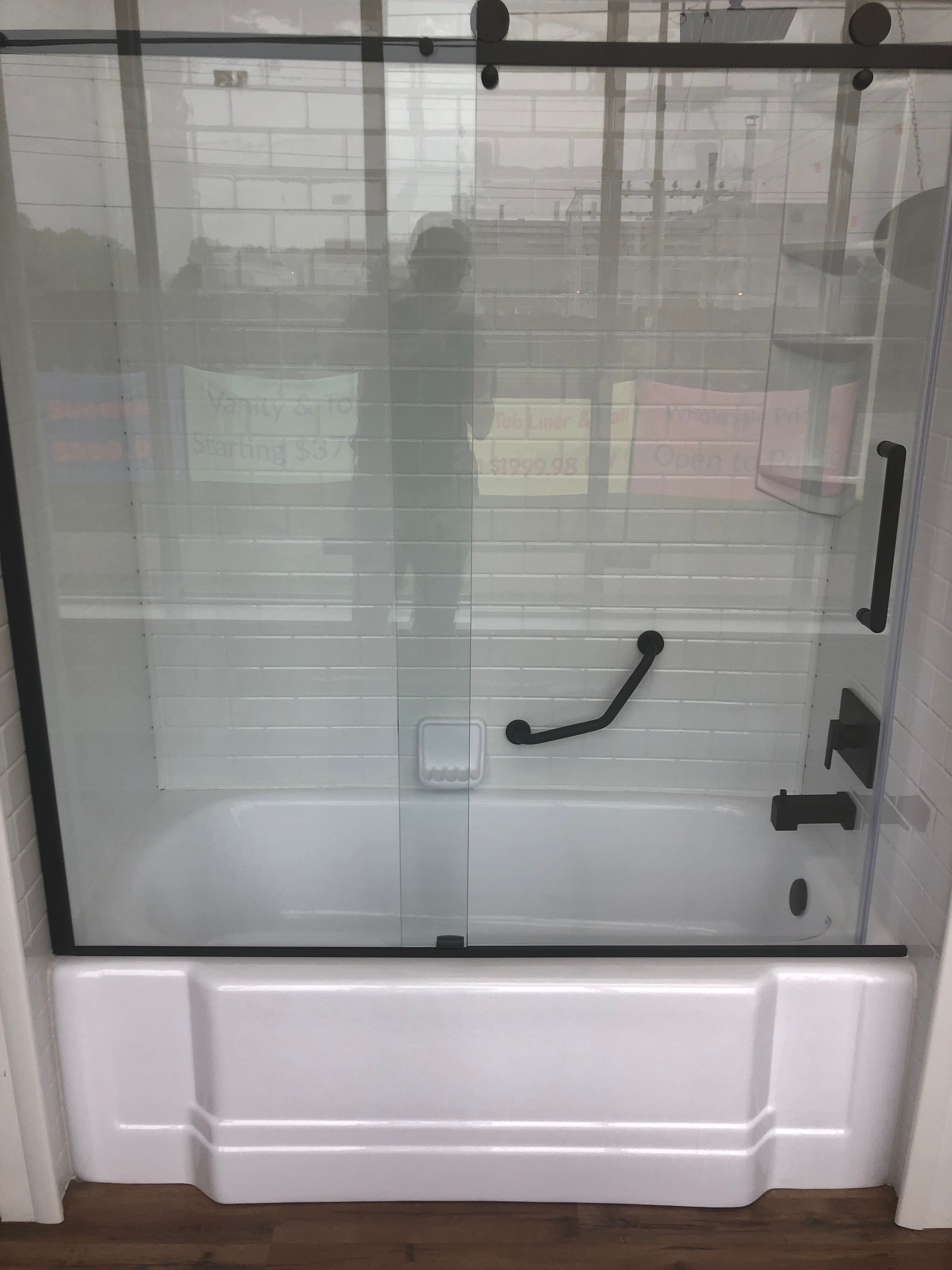 Modern bathroom with white freestanding tub, double sink vanity, wall-mounted toilet, large window with greenery view, and minimalist decor.
