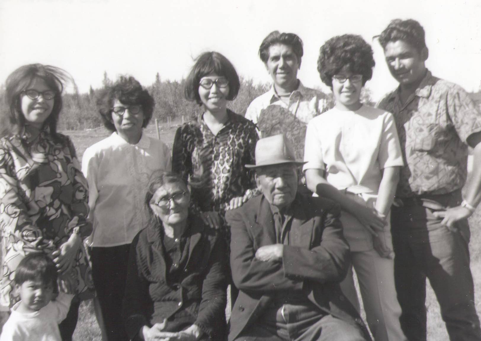 This appears to be a family photo of 4 (?) generations - none of whom we are able to identify. There is no date attached to the photo but based on the hair style, patterns of clothing and fancy winged glasses our best guess is sometime in the 60's.

*EDIT* 

This is the Roberts Family. Starting to the back left is Donna Roberts and the child is Leon Mercredi.

Next to her is Celine (Moberly) Roberts, Vina (Roberts) Marten, Norbert Roberts, Emilie Roberts, Chuck Badger (former spouse to Emilie)
Norbert’s parents in front Claudell and Thomas Roberts’s

2000.35.02.12 / Bell, Lorna
