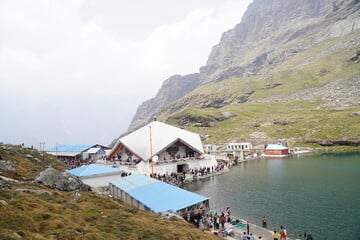 Mountain lakeside village with white-roofed buildings and turquoise water beneath steep rocky cliffs