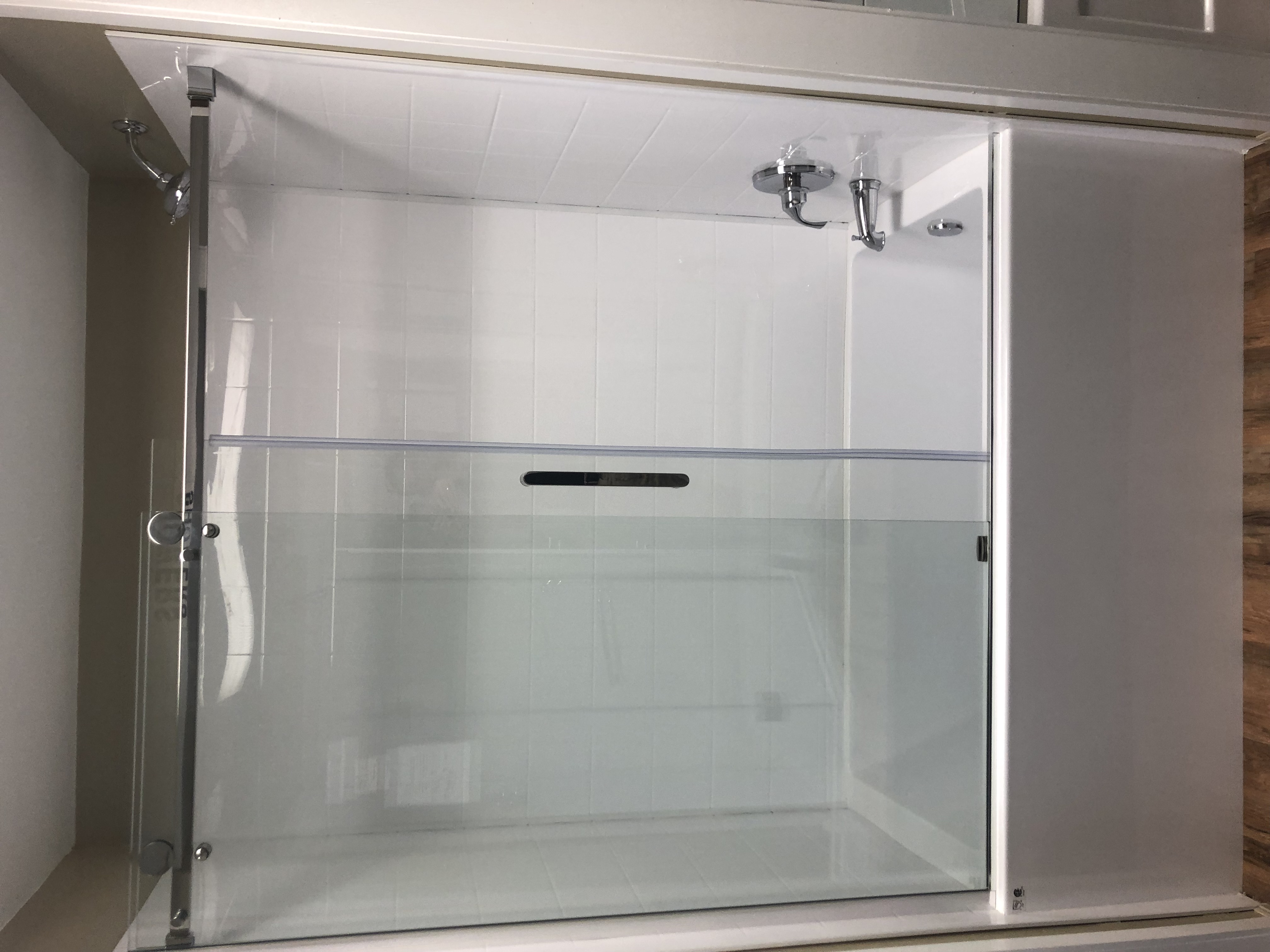 Modern minimalist bathroom with gray tiles, floating wooden vanity, large mirror, freestanding bathtub, glass shower, and ambient lighting.