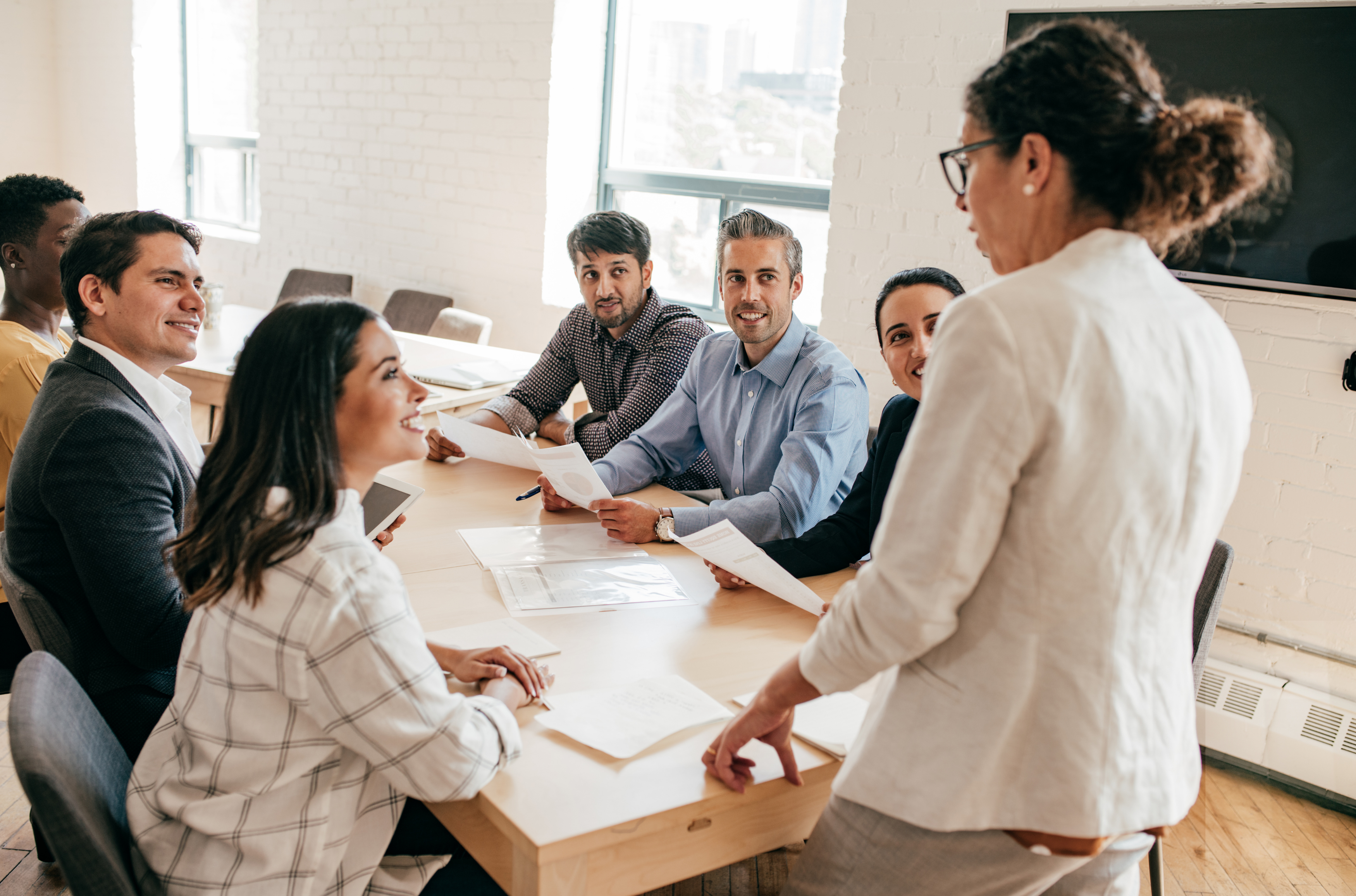 Business team in a meeting around a conference table, discussing documents with a presenter.