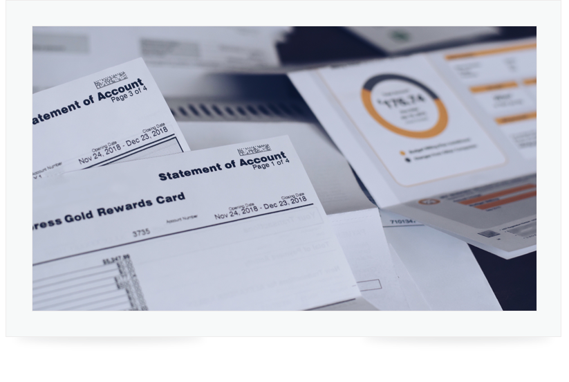 Close up of multiple bills scattered over a desk.