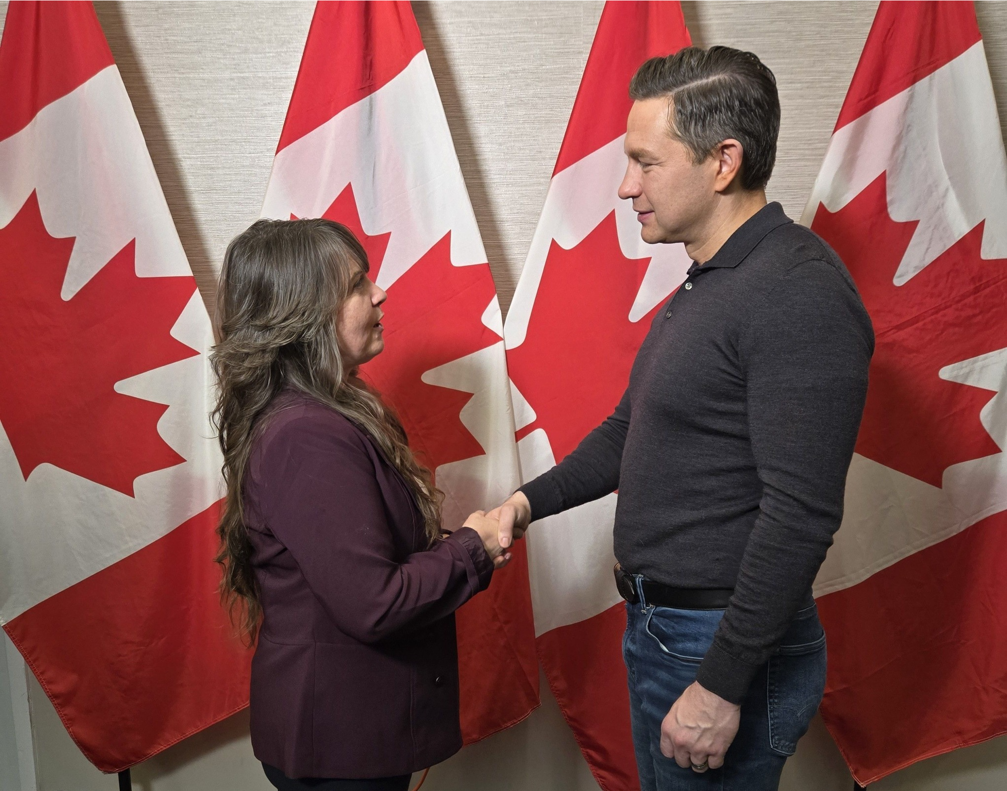 Smiling woman with long blonde hair wearing a black blazer in a bright, modern office setting.