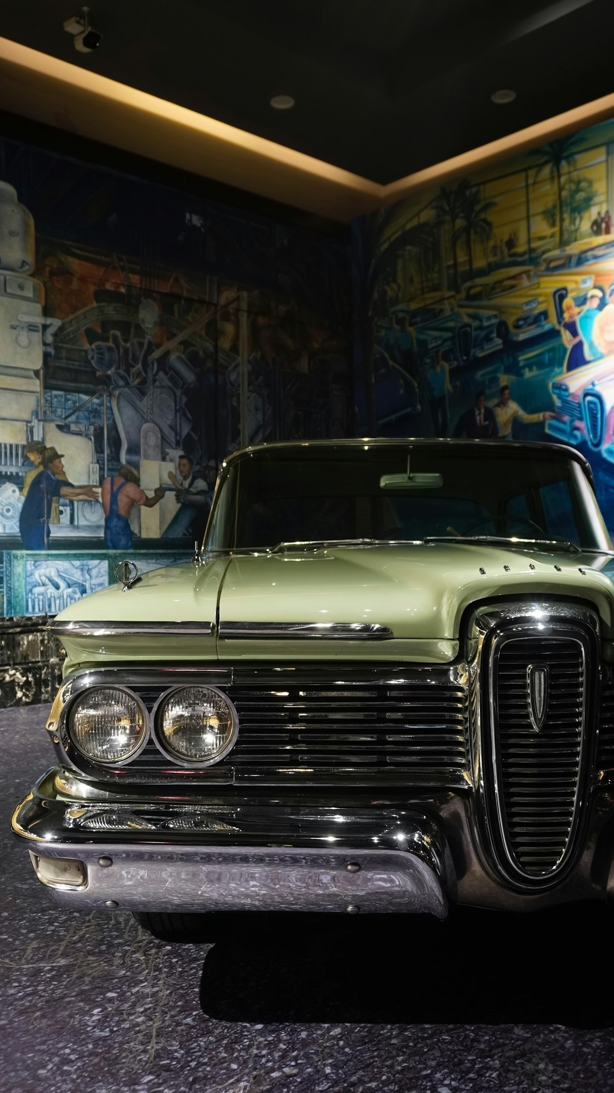 A green car parked in front of a mural