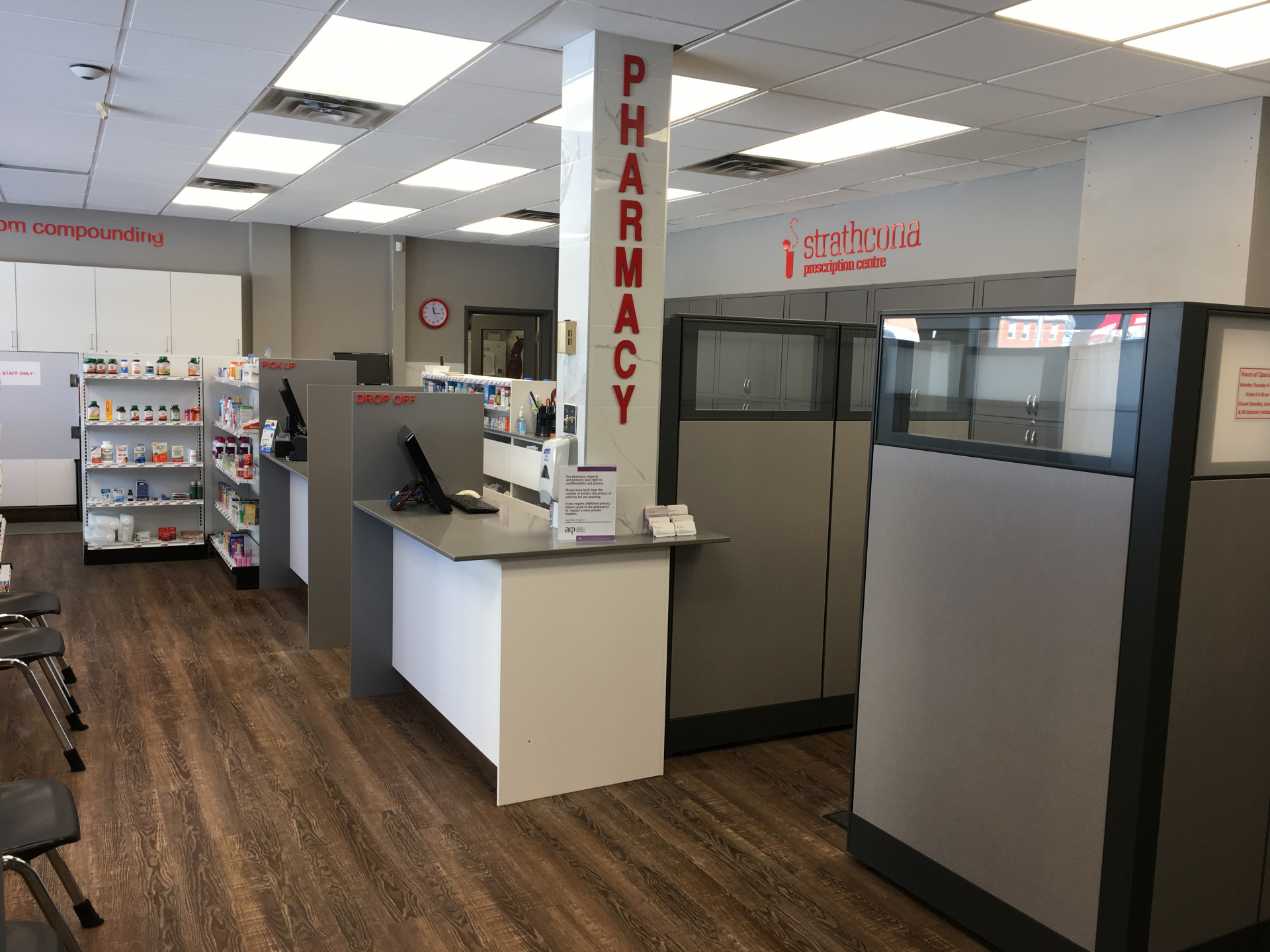 Interior of Strathcona Prescription Centre pharmacy with pickup and drop-off counters, medication shelves, and consultation cubicles