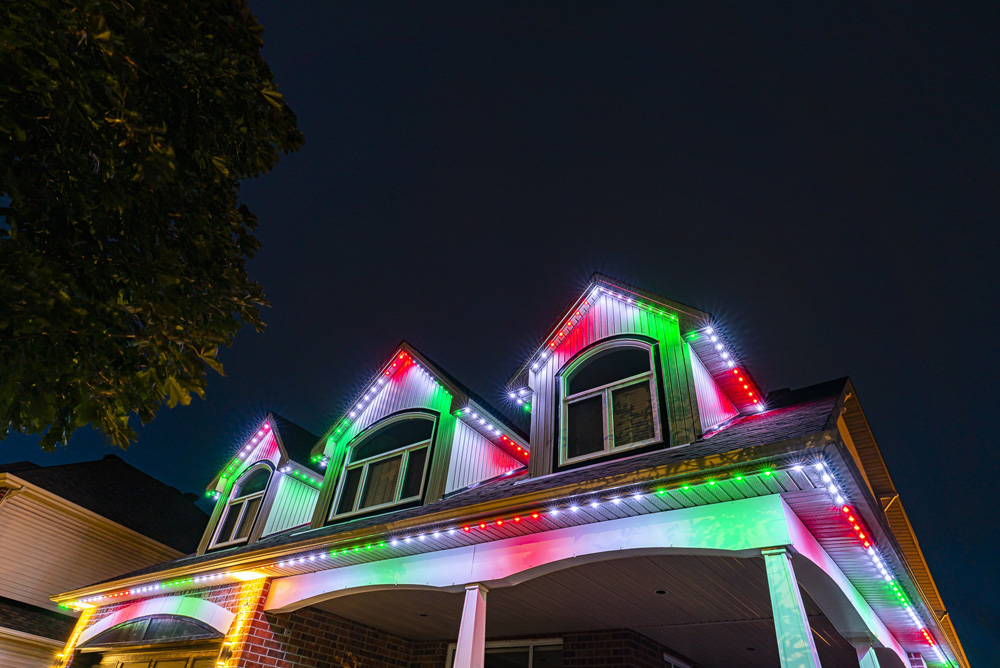 Red, white, and green lights on a house in the evening.