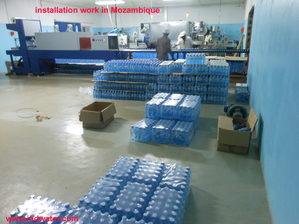 Modern office corridor with large windows, indoor plants, and marble flooring.