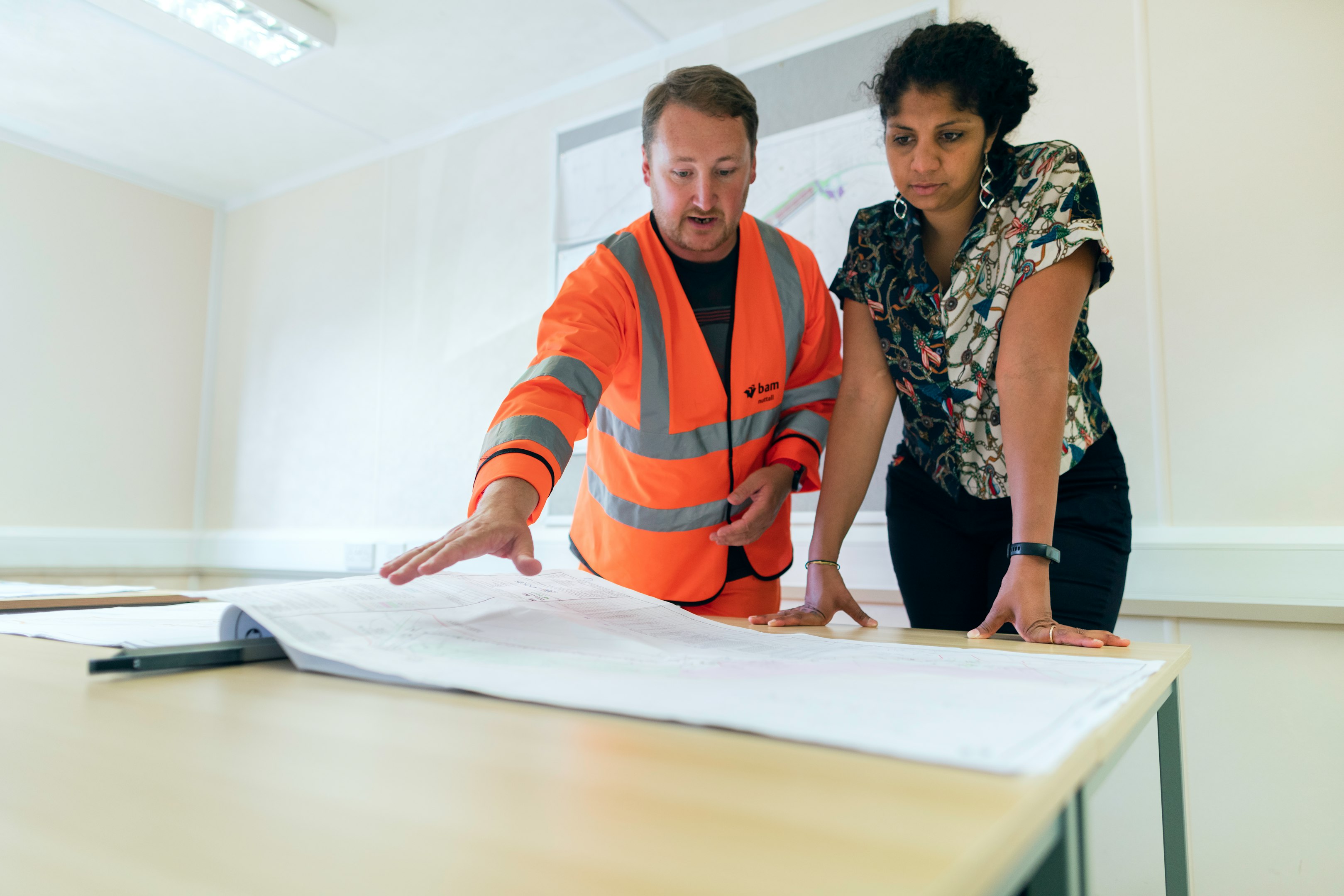 Business professional using tablet and desktop computer in modern office with colleagues analyzing data