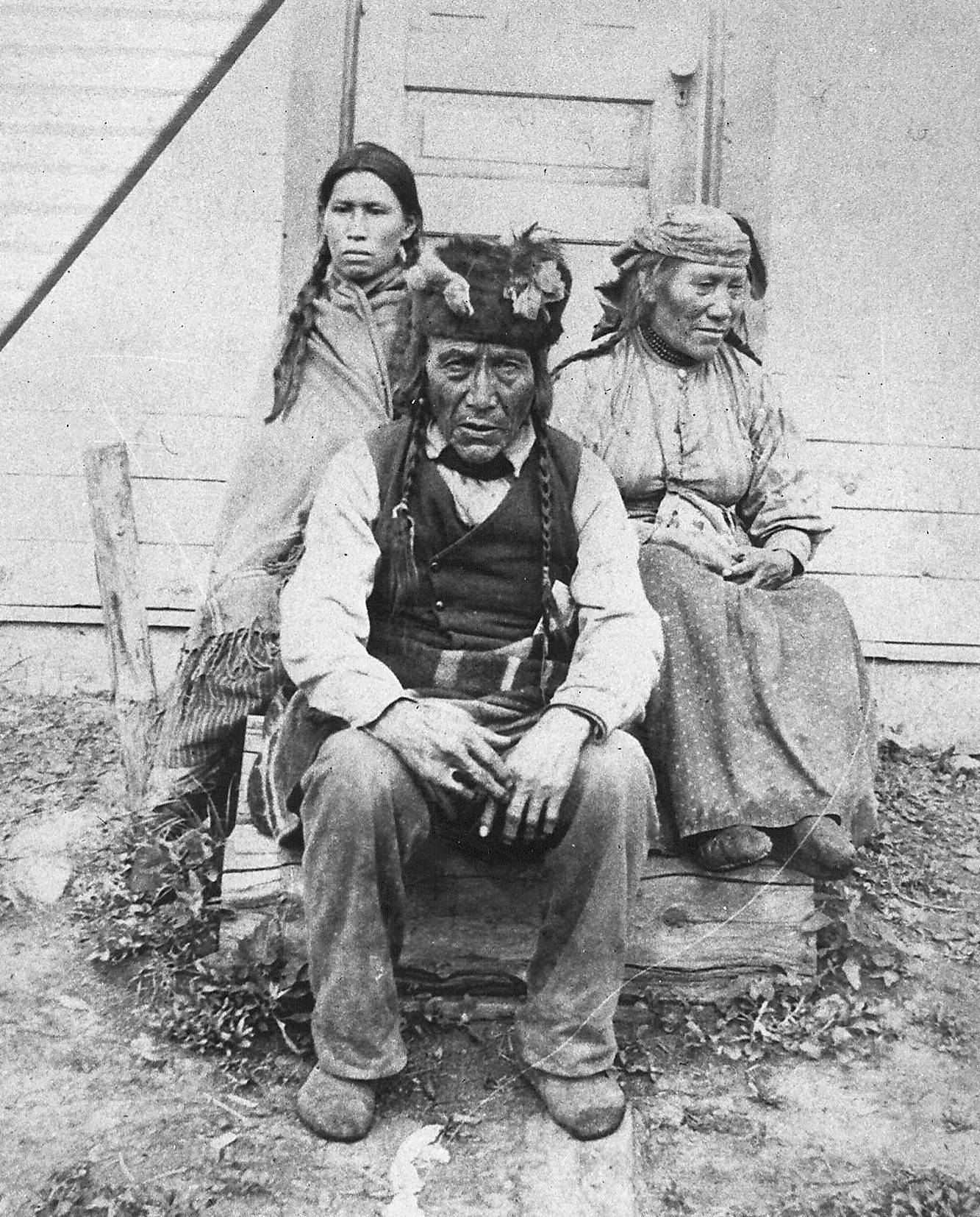 The description we have for this photo is "Chief and Family - Peace River area". If you look closely at the right hand of the man in front,it appears to be disfigured which may be helpful in identifying him! It is also possible the hand is fine and rather the image is distorted / shadowed due to rudimentary photography.
2015.27.29 / Nugent, Mike

---EDIT---

This gentleman is Duncan Testawitch