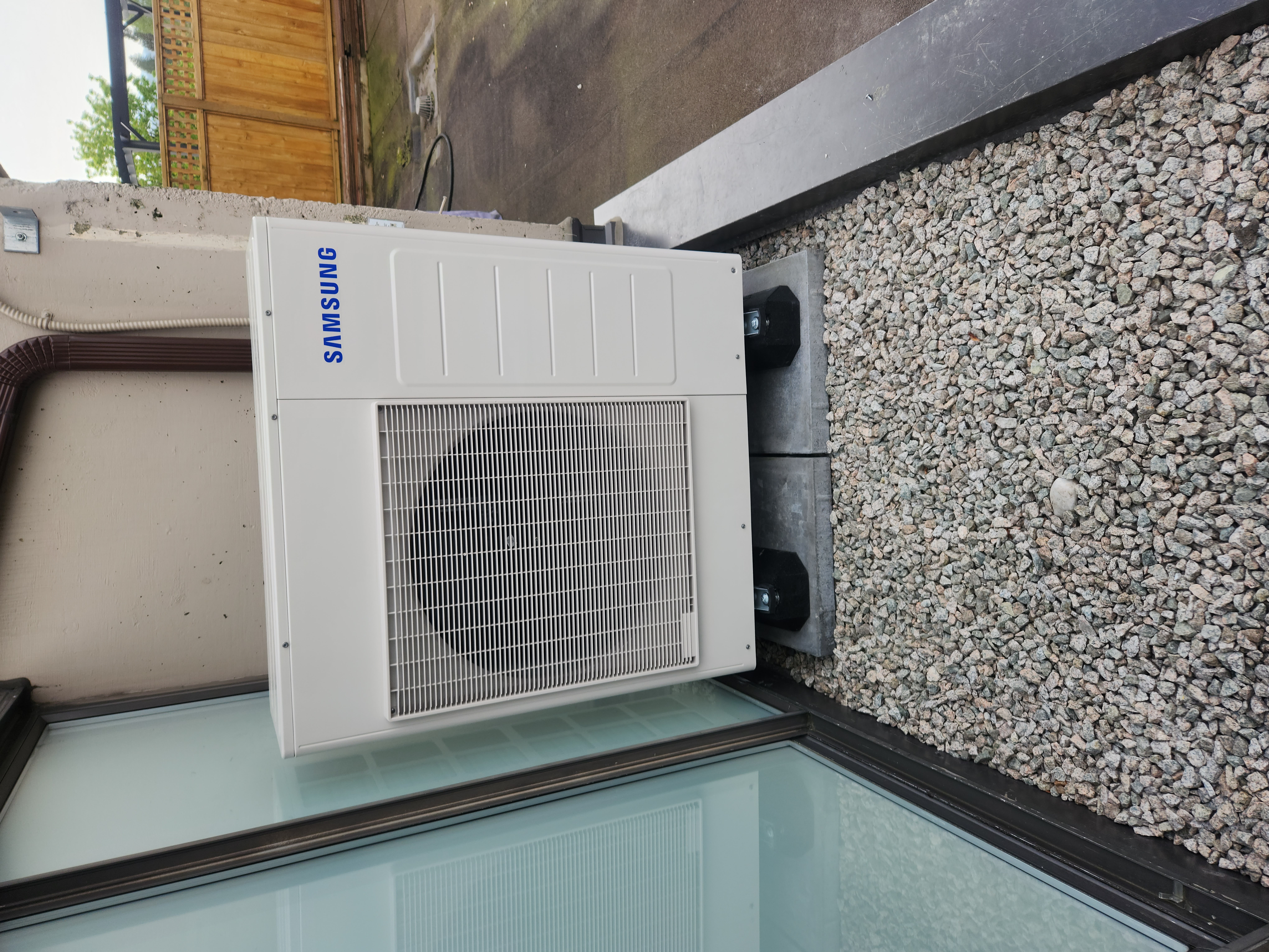 Modern patio with outdoor dining table, glass doors leading to a stylish kitchen, and potted plants.