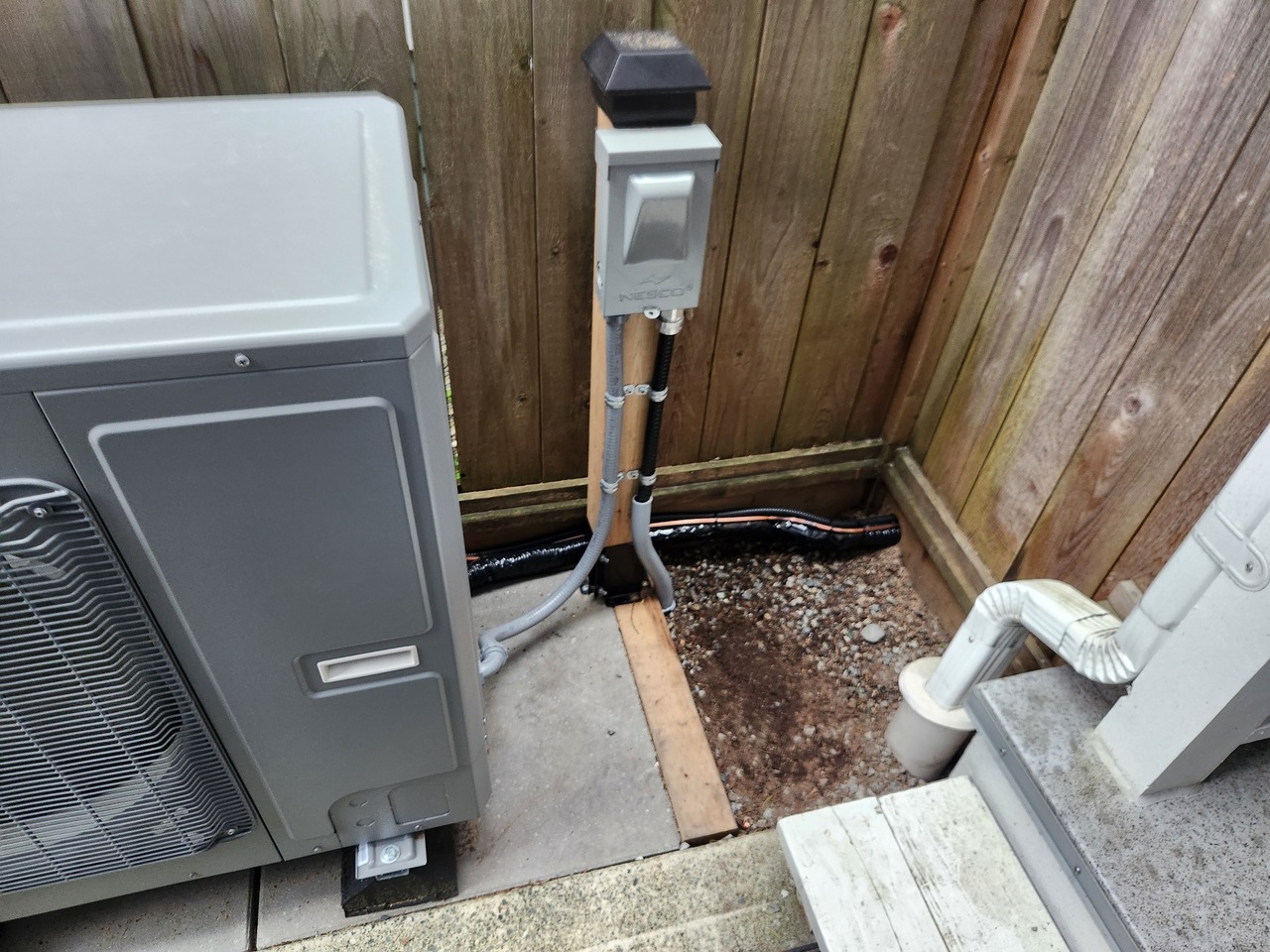 Outdoor air conditioning units on a modern patio with plants and sunset view in the background.