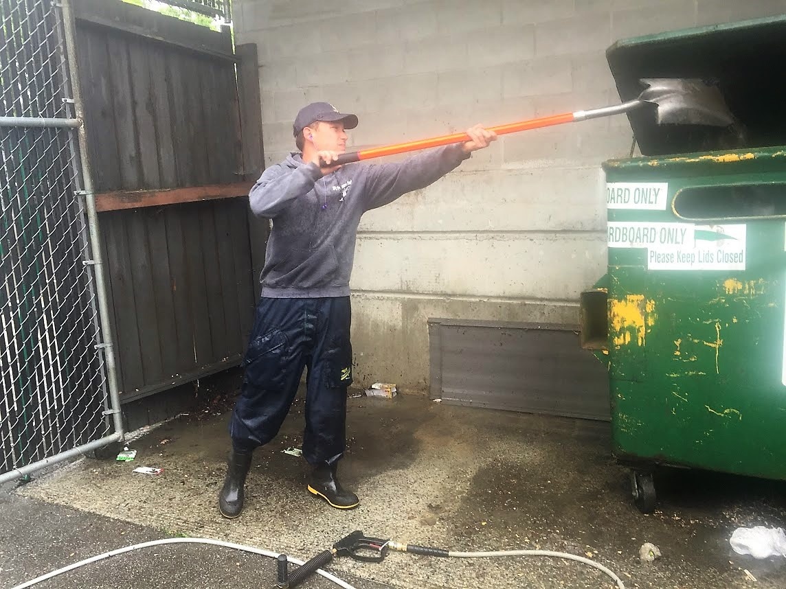 Shoveling to pick up garbage debris around garbage bin areas before pressure washing.