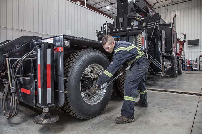 Mechanic tightening wheel lug nuts on heavy-duty tow truck in repair garage