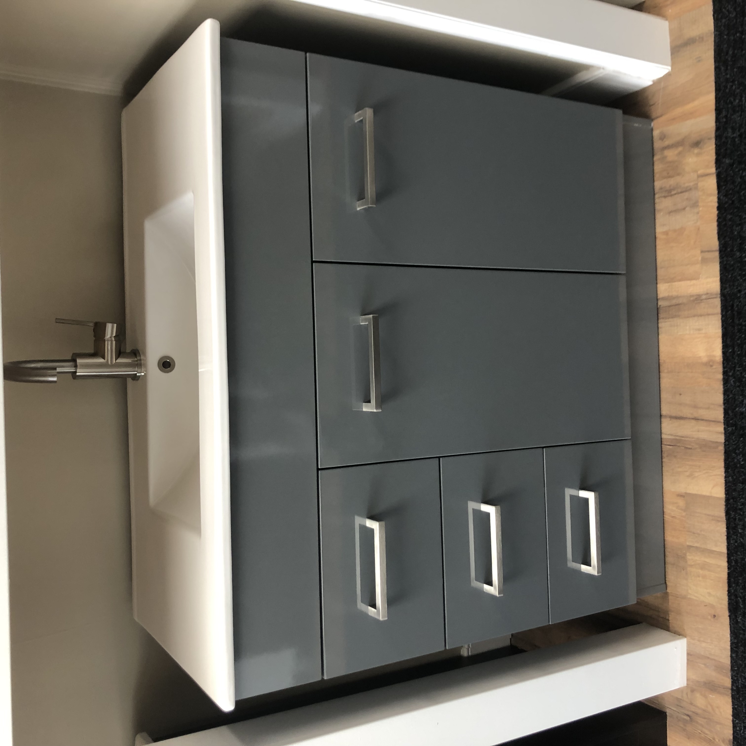 Modern bathroom interior with freestanding bathtub, wall-mounted sink, large window, towel rack, and decorative plants.