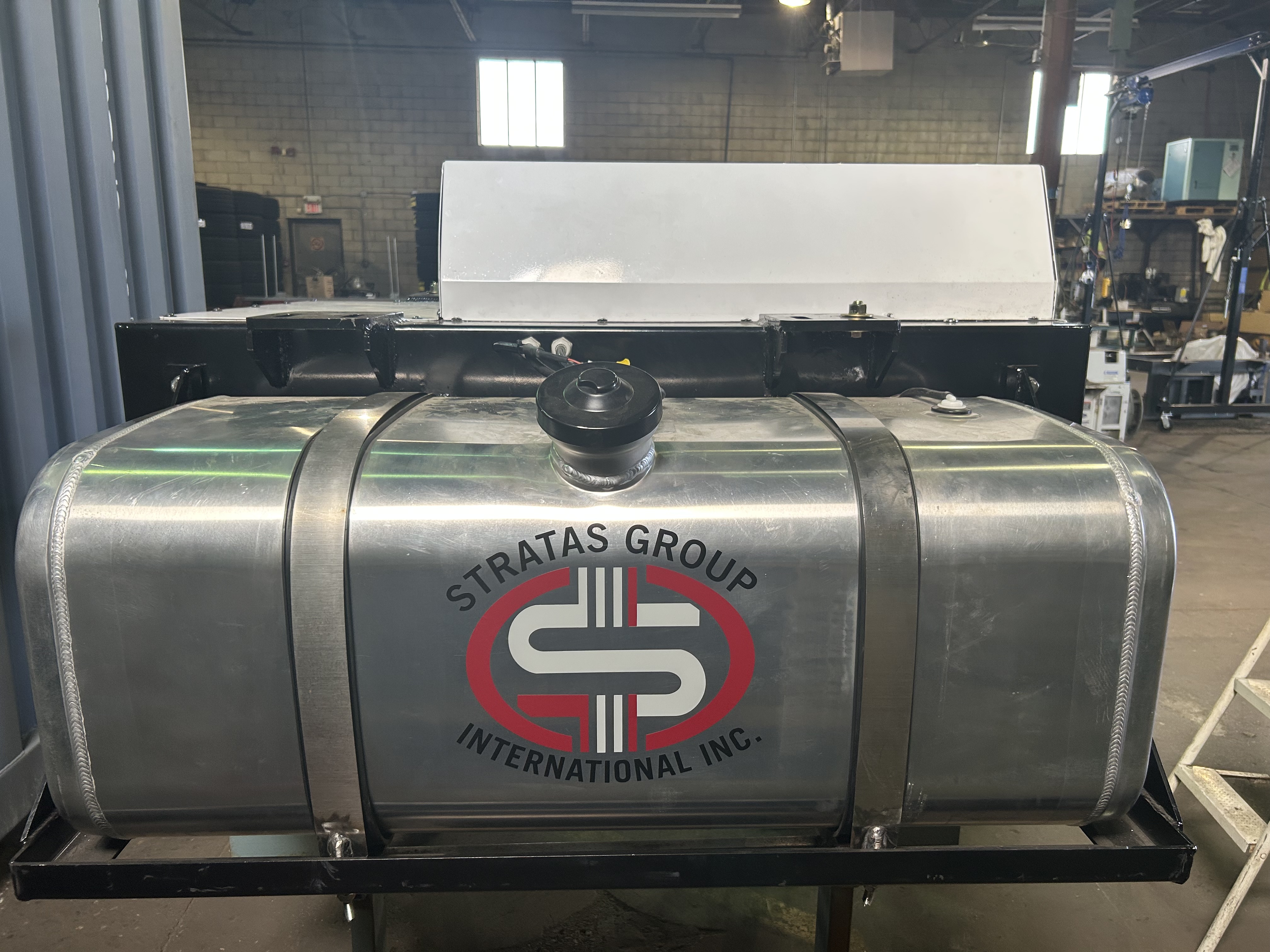 High-performance automotive engine with tire on a workshop floor, surrounded by industrial equipment and machinery.