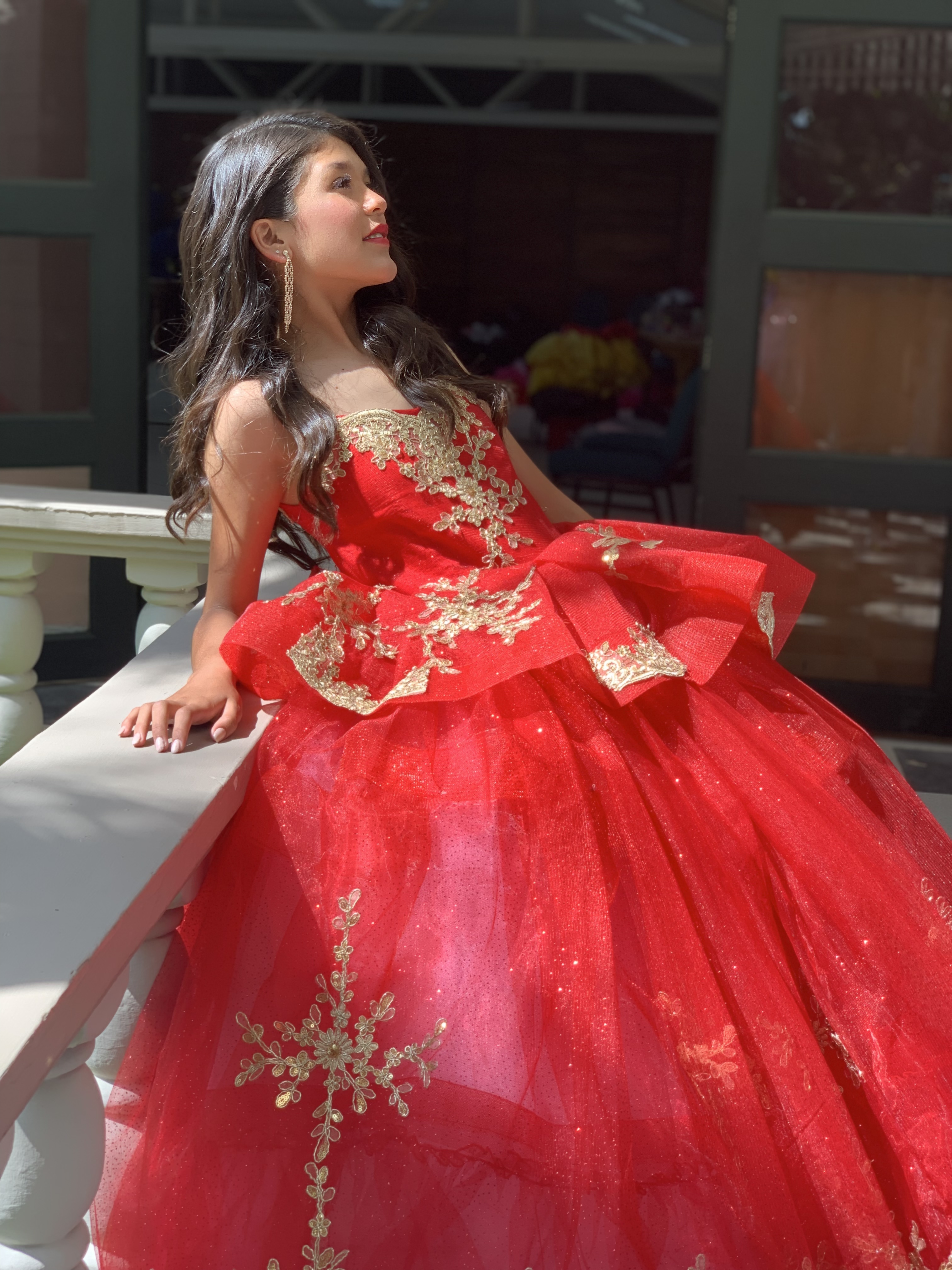 Woman in an elegant blush pink gown standing in a bright, plant-filled room.