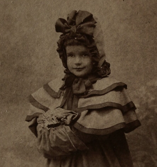 Woman writing in a notebook with two children and a man in the background at a cozy home setting.
