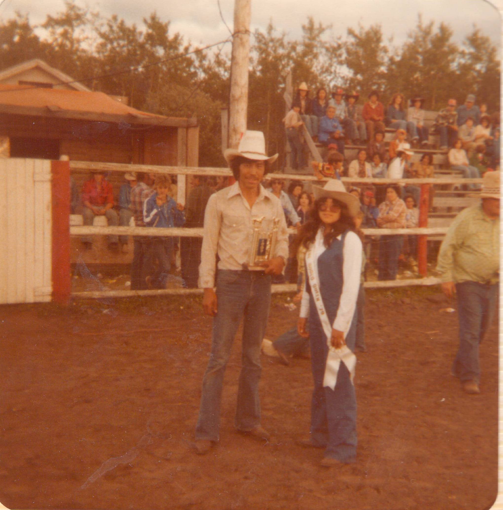 Anyone remember who was rodeo queen in 1979? The lady on the right is wearing the rodeo queen sash from that year! We also are unsure of the gentleman on the right. It seems he has won a trophy that has horses on the top. Any leads are appreciated!
*update*
Thanks to our Facebook Friends we are able to identify the gentleman on the left as Clarence Fournier and the rodeo queen on the right as Sherry Kazonay

2019.24.264 / Lizotte, Maria