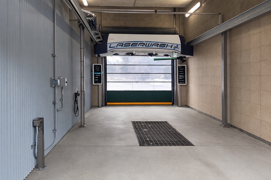 Sleek white sports car with aerodynamic design and spoiler, parked inside a modern car wash garage.