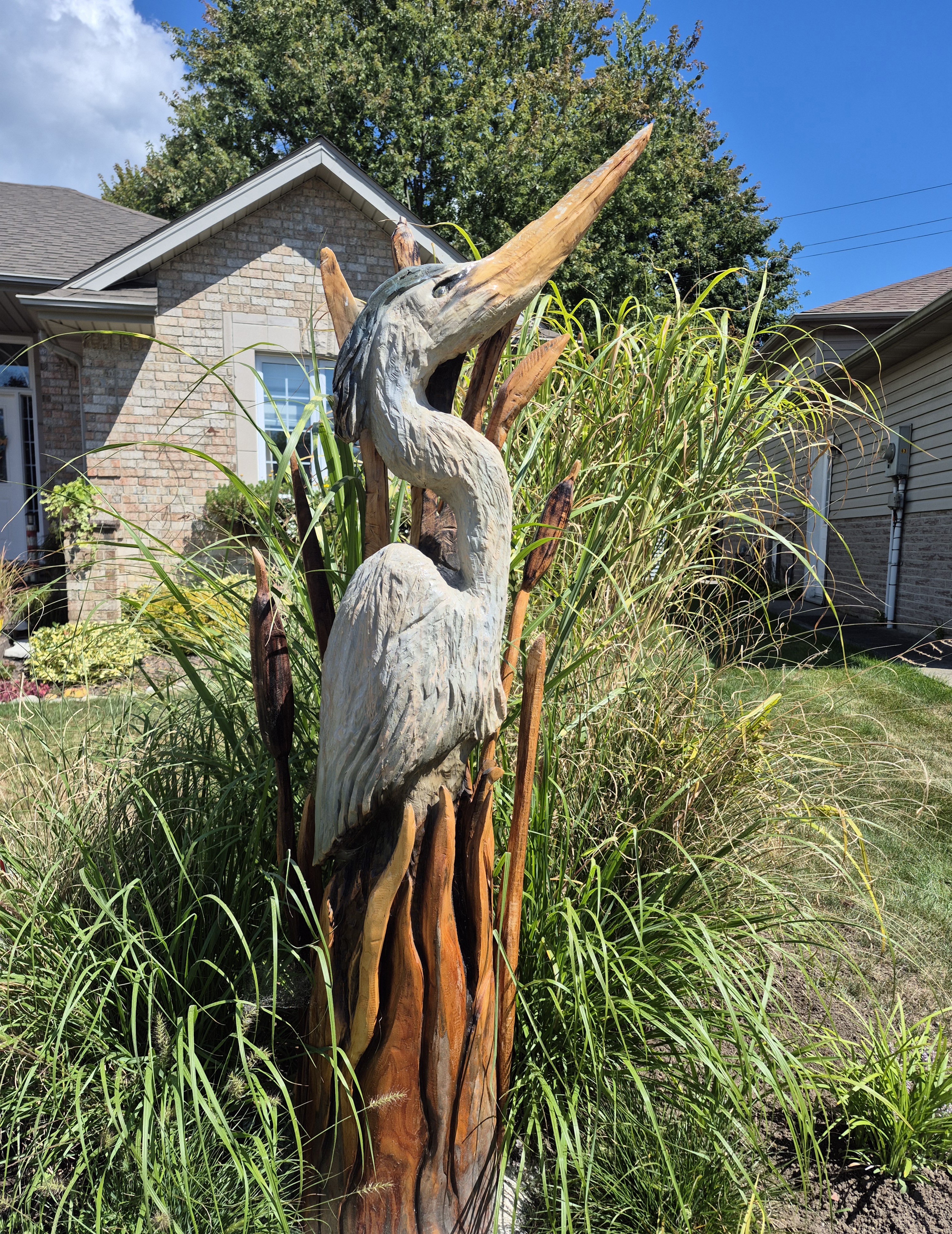 Woodcarvers using chainsaws to create animal sculptures in a garden workshop