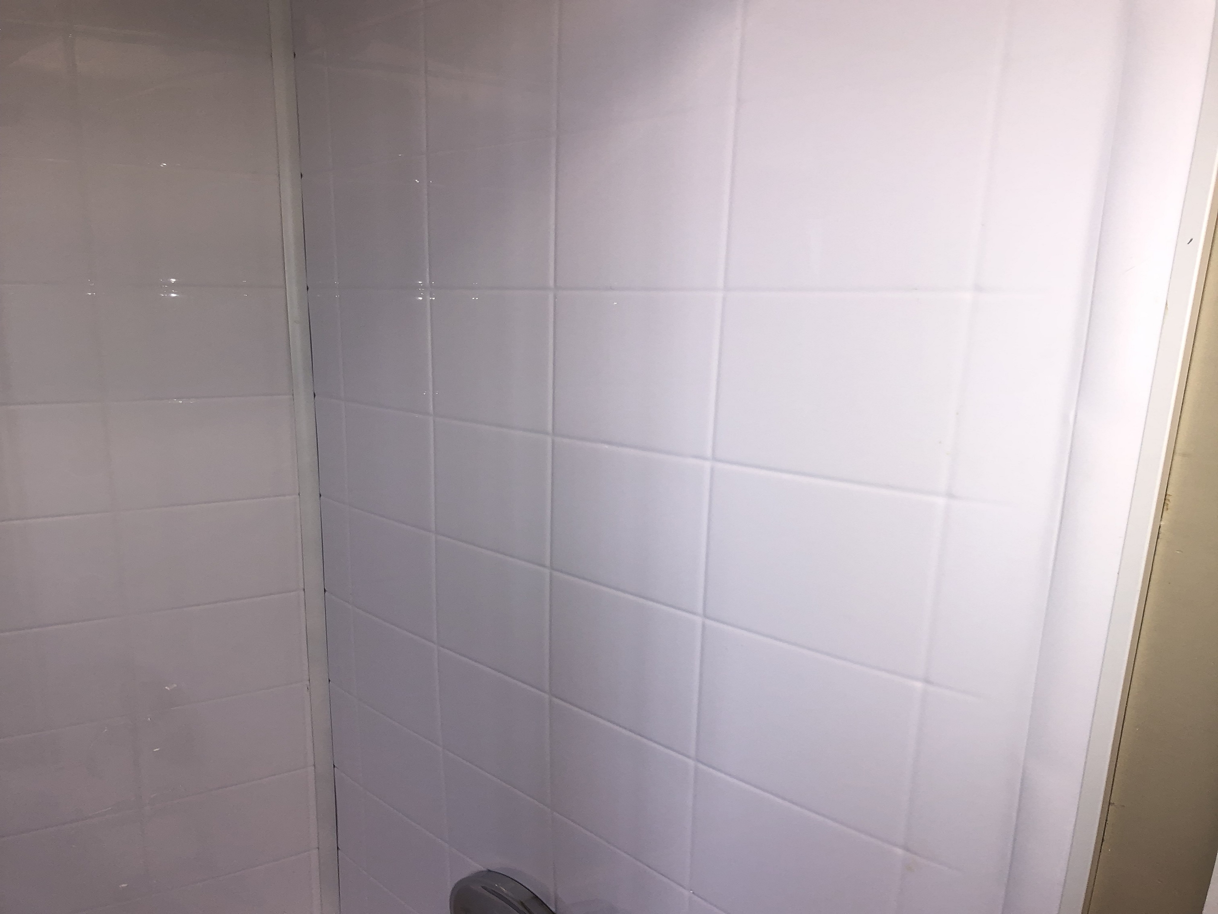 Modern bathroom with freestanding tub, large window, plants, and backlit mirror.