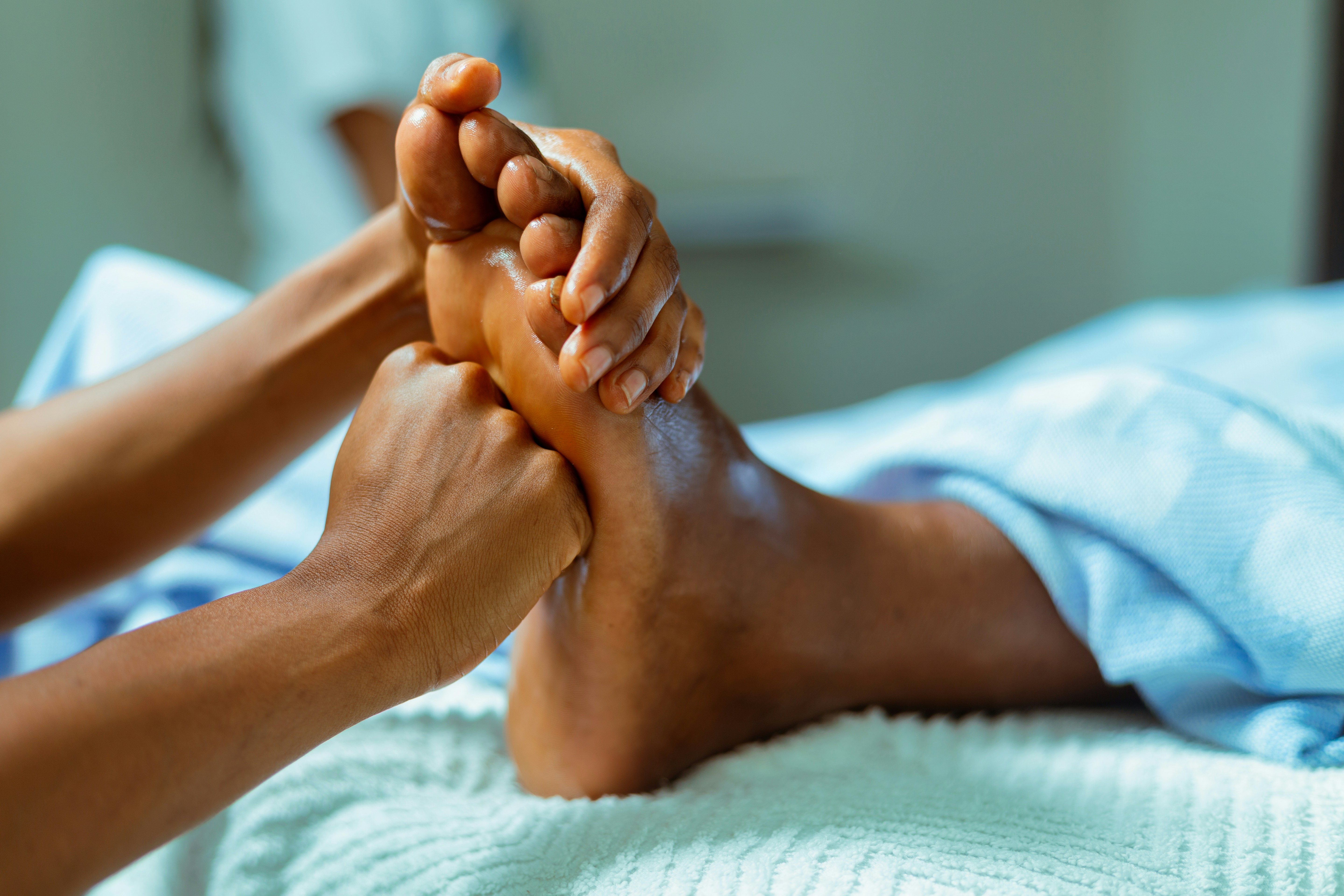 Close-up of a person receiving a relaxing foot massage on a white towel. Close-up of a person receiving a relaxing foot massage on a white towel.