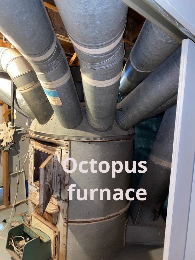 Vintage octopus furnace with numerous metal ducts in a basement.
