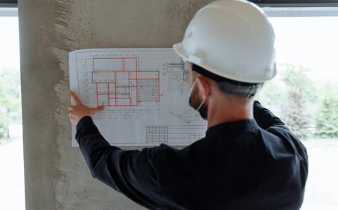A man in a hardhat looking at a blueprint