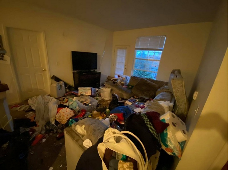 Living room in neglected property condition with clutter accumulation, disrupted organization, and environmental overwhelm requiring structured restoration