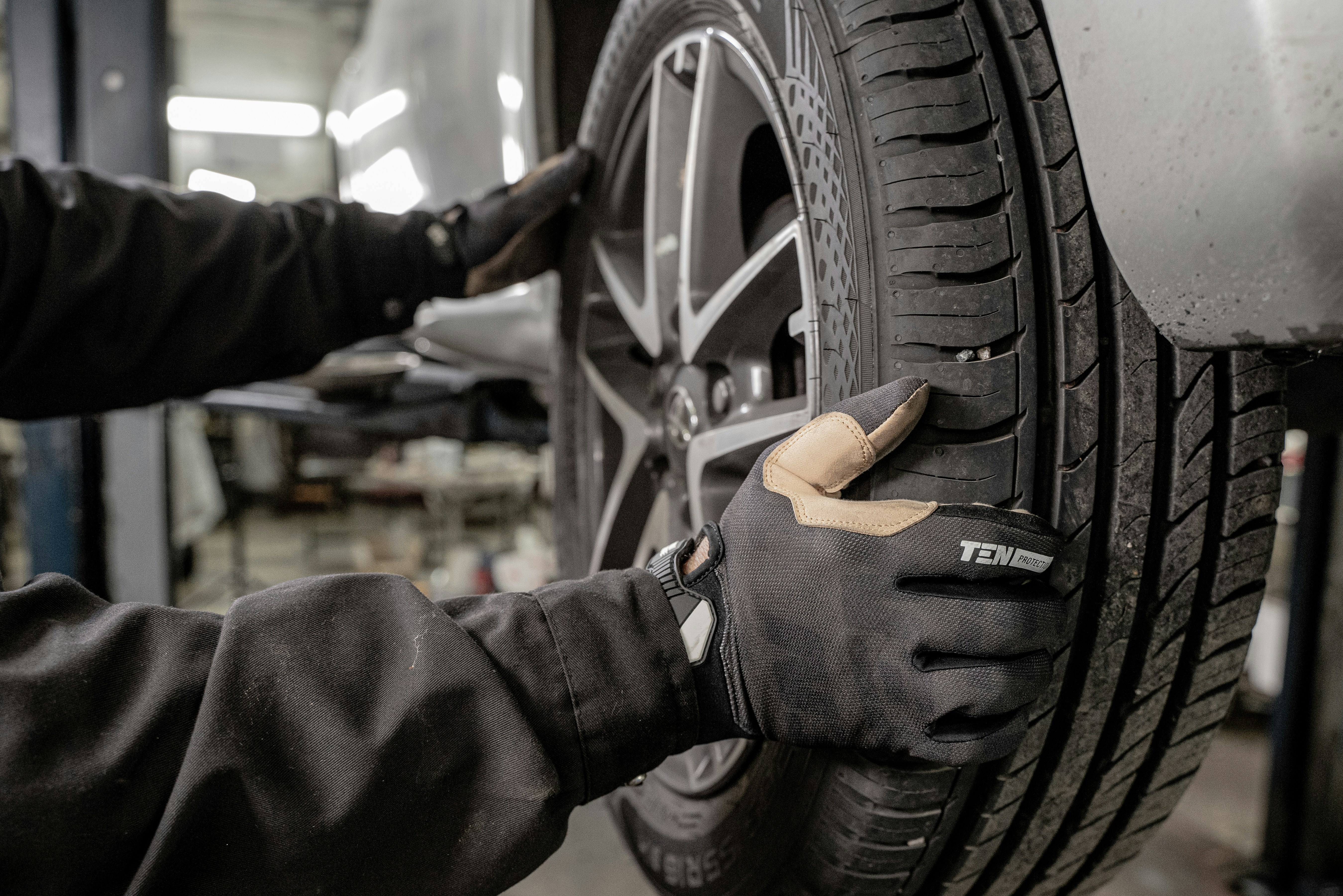 Two auto mechanics reviewing a clipboard in a car repair workshop with vehicles in the background.