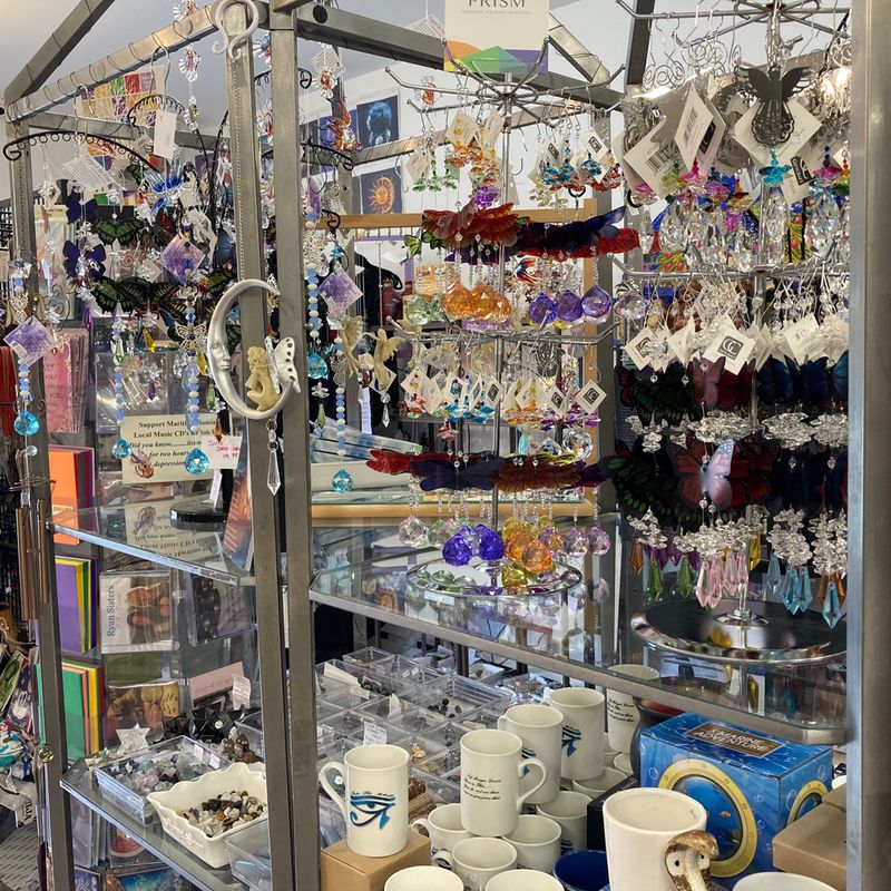 Colorful gift shop display with hanging ornaments, crystals, mugs, and trinkets.