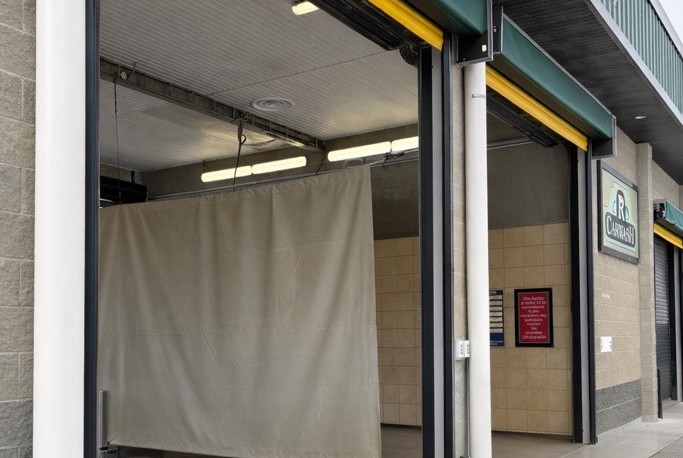 Luxury sports car inside automatic carwash with R Carwash sign.