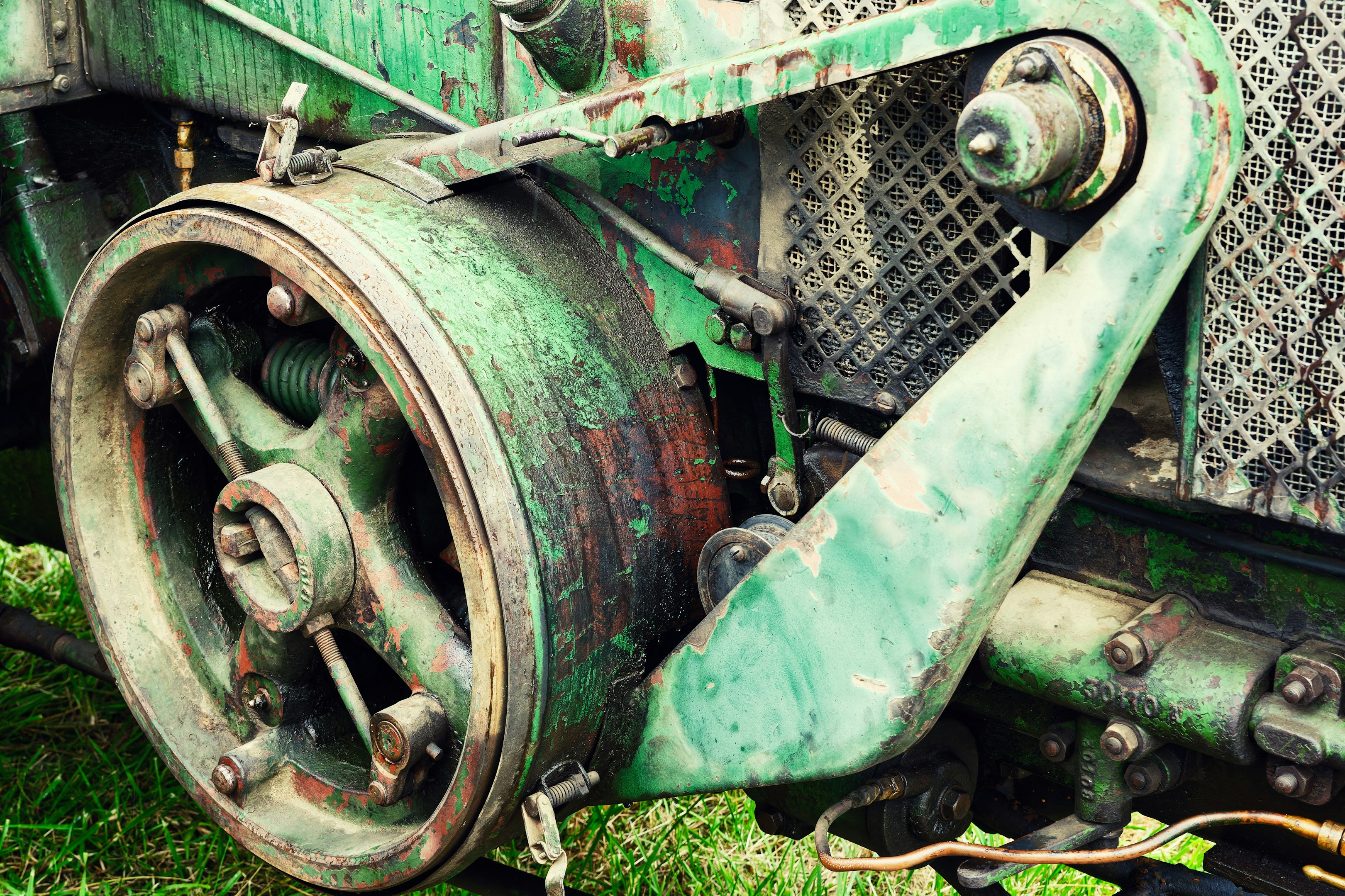 Close-up of vintage green industrial machinery with rusted metal gears and components.