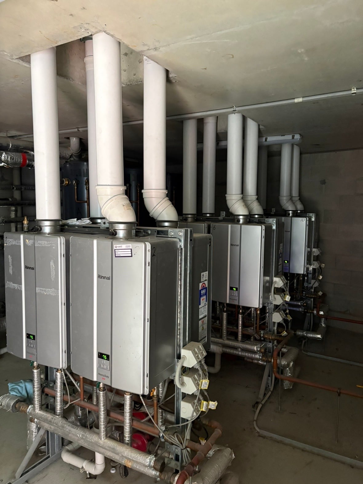 Engineers inspecting industrial boiler and pump system in a modern building mechanical room