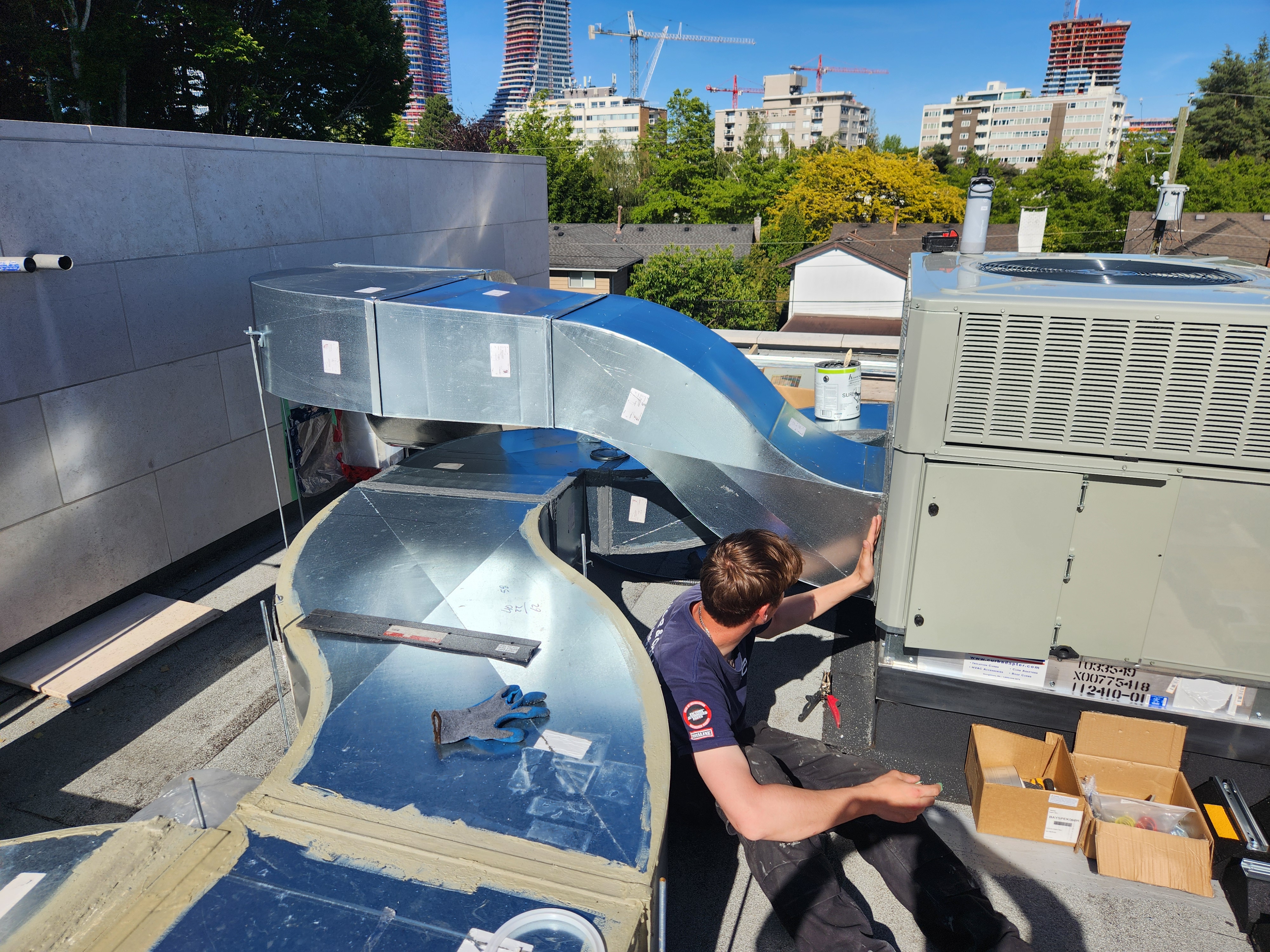 Modern open-plan living room and kitchen with large windows, fireplace, and a central island with a sink, featuring a cozy seating area and stocked beverage coolers.