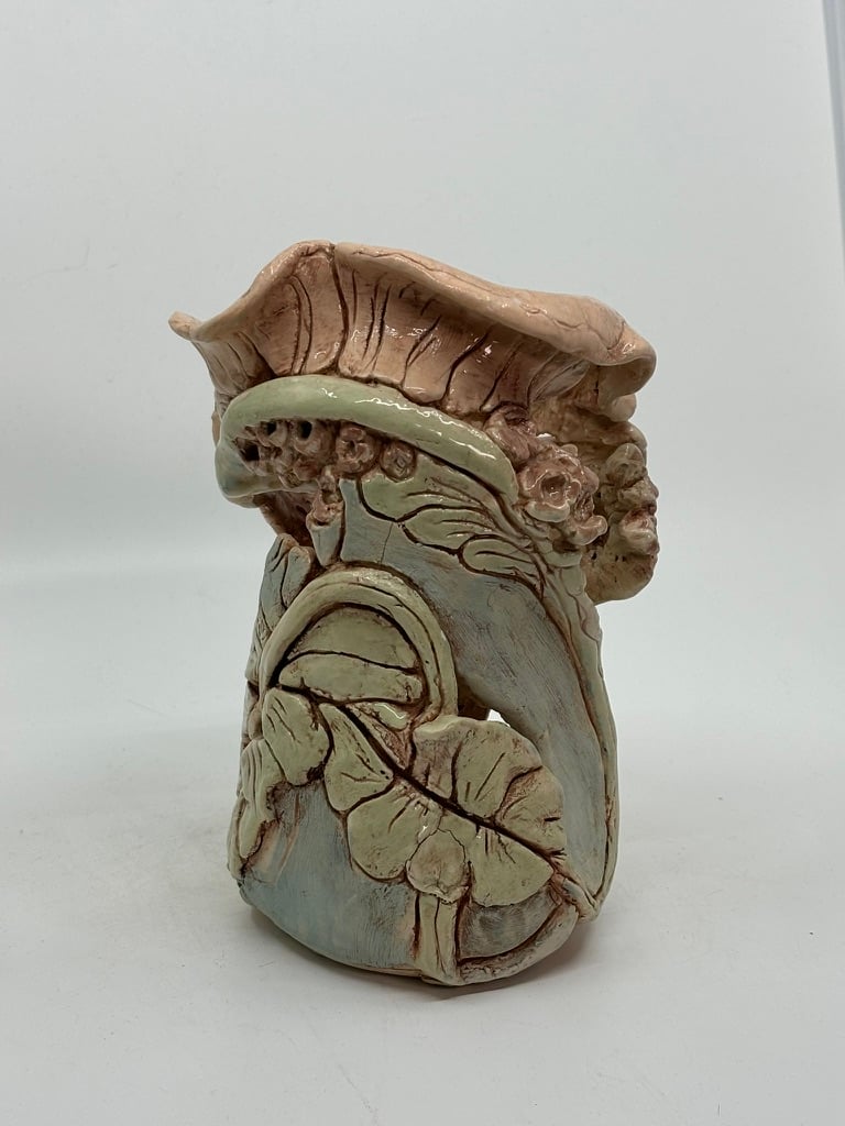 Ceramic sculpture with intricate leaf and floral designs on a textured surface
