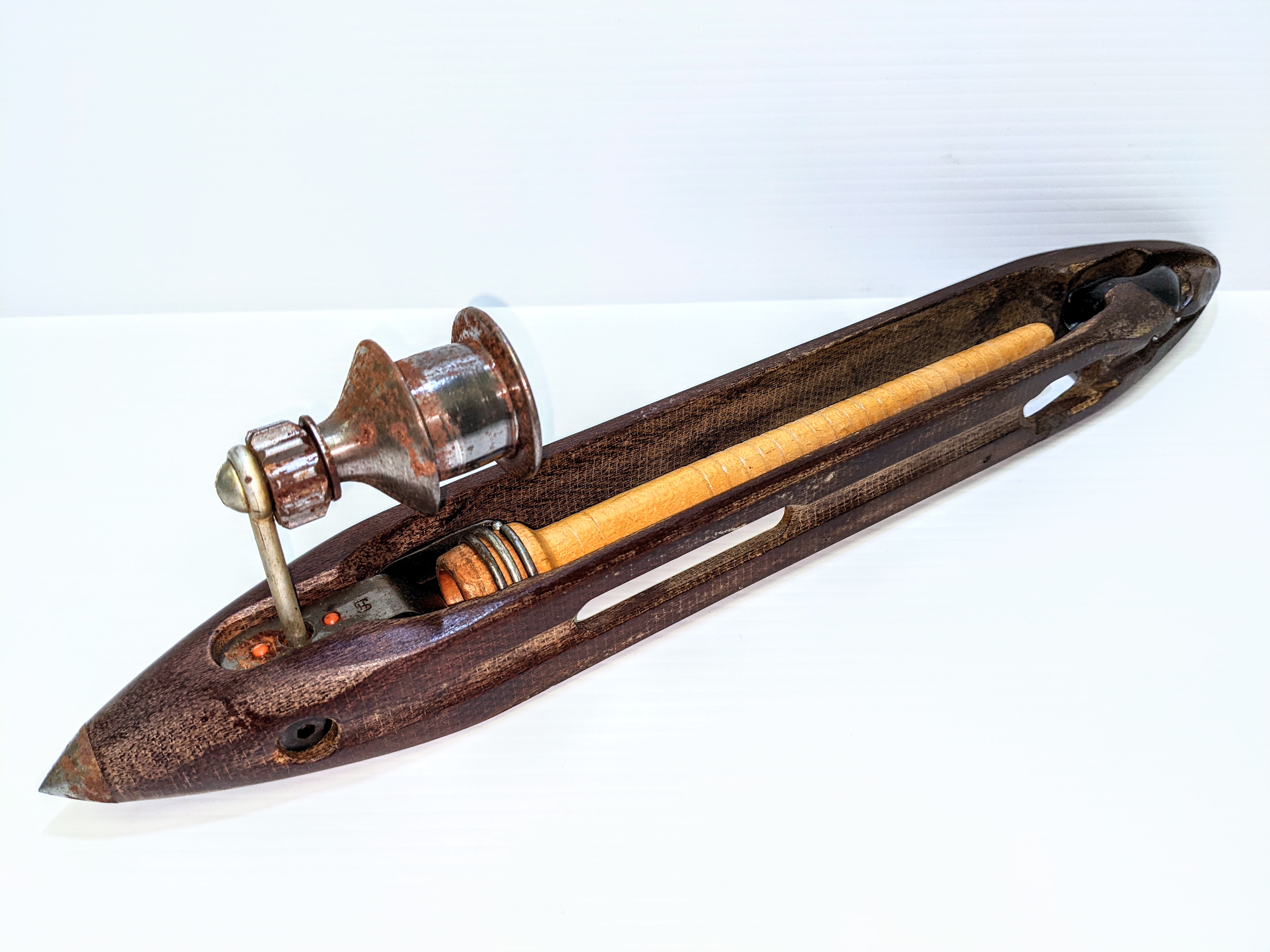 This is an upcycled candle holder! The original purpose of the pointy device was a weaving loom shuttle. Made and patented by the "Shambow" company in 1937


"The main object of the invention is to provide a reinforcing or supporting means for Shuttles adapted to be located at the point where breakage is most likely to occur for reinforcing one or both lateral portions of the shuttle body in such a manner as to distribute the strain caused by forcing a bobbin into the thread delivery end of the shuttle and thus prevent breakage of the shuttle."

which is quite a mouthful! The protrusion out the top is where the device has been upcycled to a candle holder - with remnants of wax inside!
2017.22.115 / Creighton, Harold + Evelyn
16/08/2022