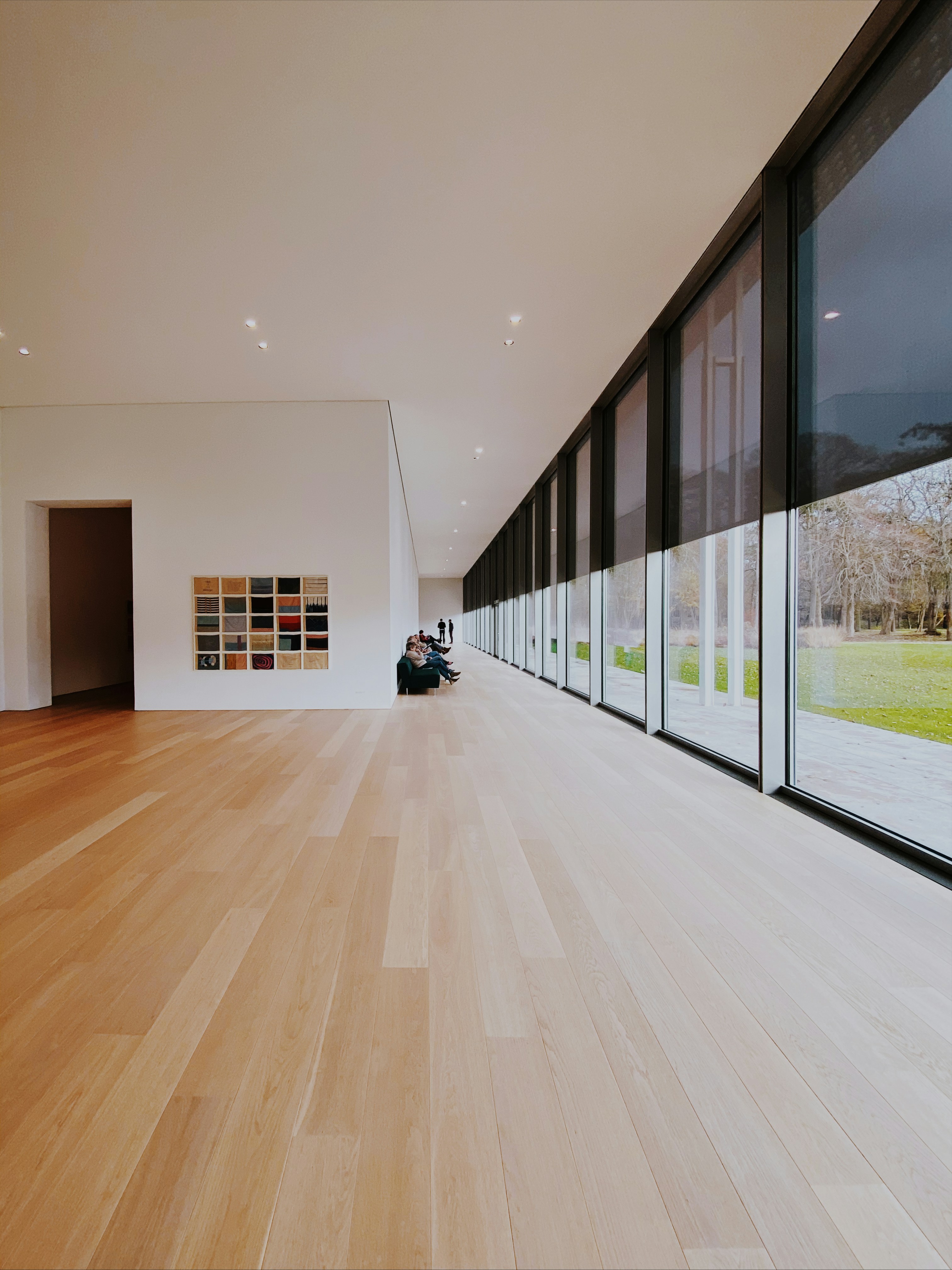 Modern office lounge with greenery, large windows, and people collaborating around a table.