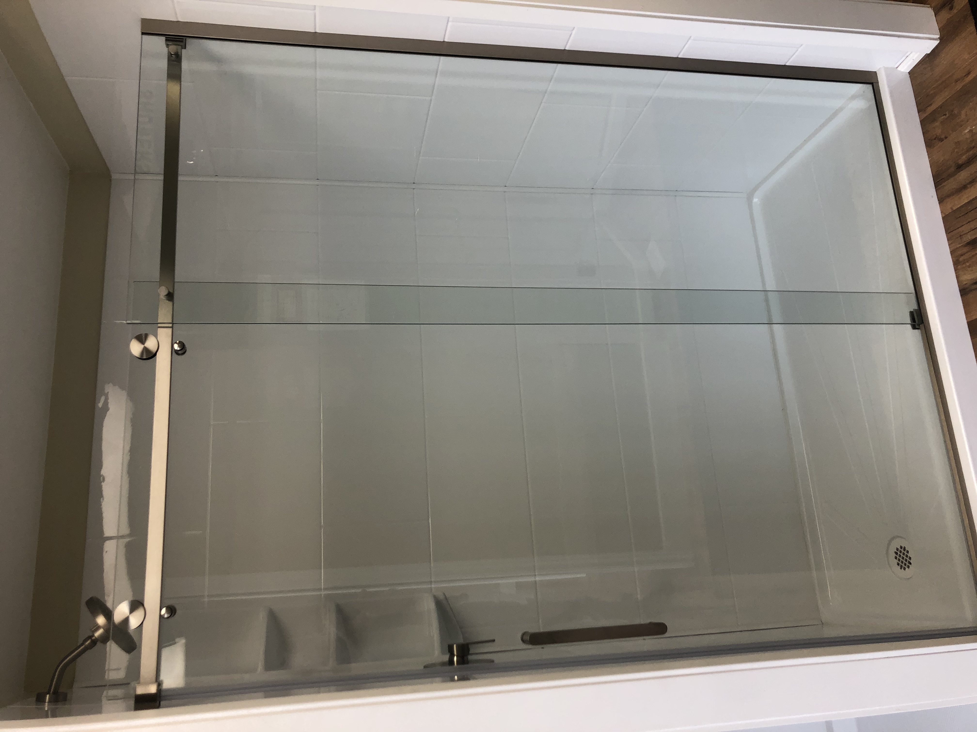 Modern bathroom with white toilet and vanity, large mirror, indoor plants, and city view through floor-to-ceiling windows.