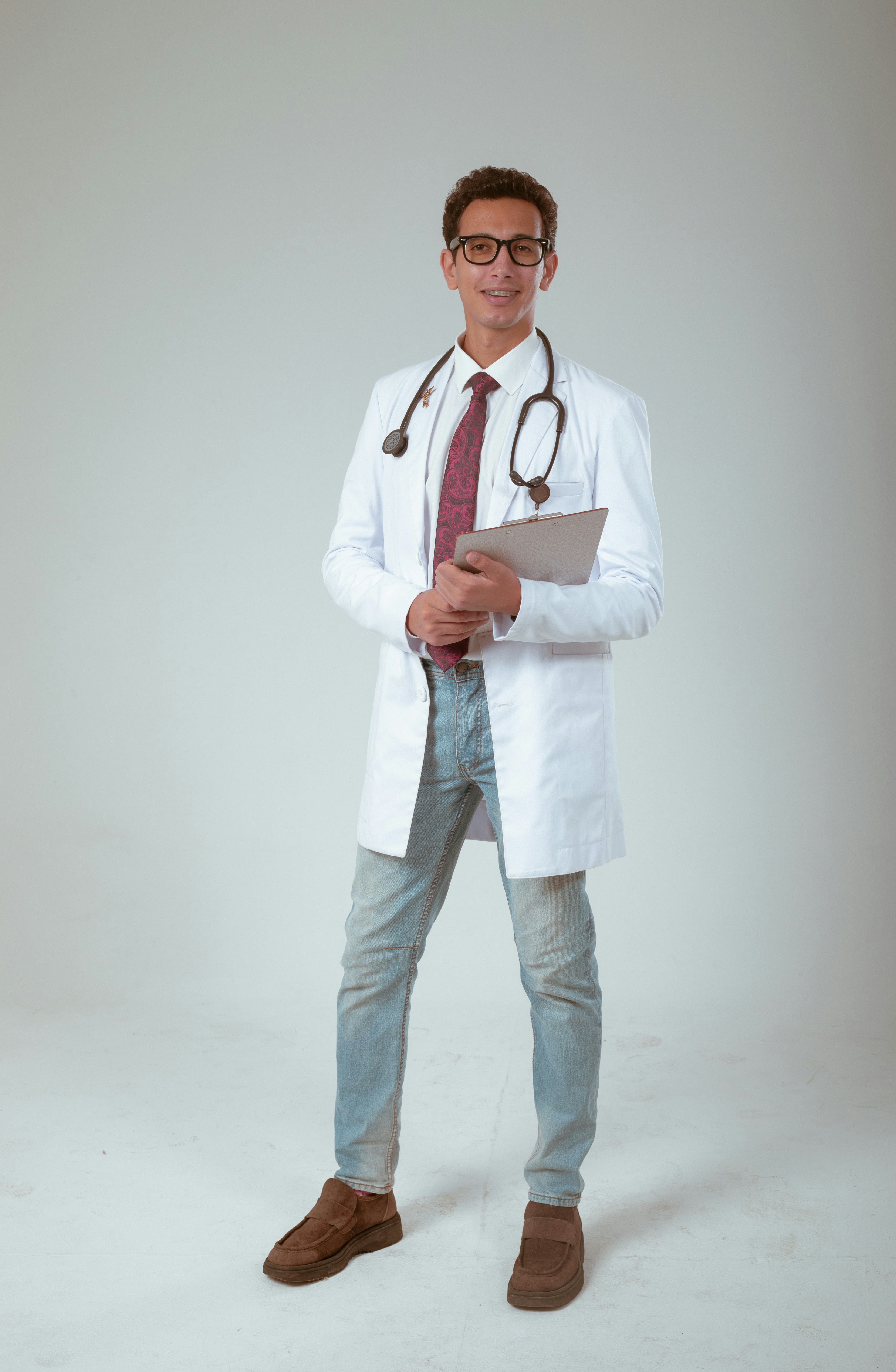 Portrait of a male doctor in glasses wearing a blue striped shirt with MH Medical Clinic logo