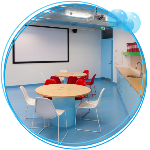 Clean room with a counter and whiteboard with tables and chairs.