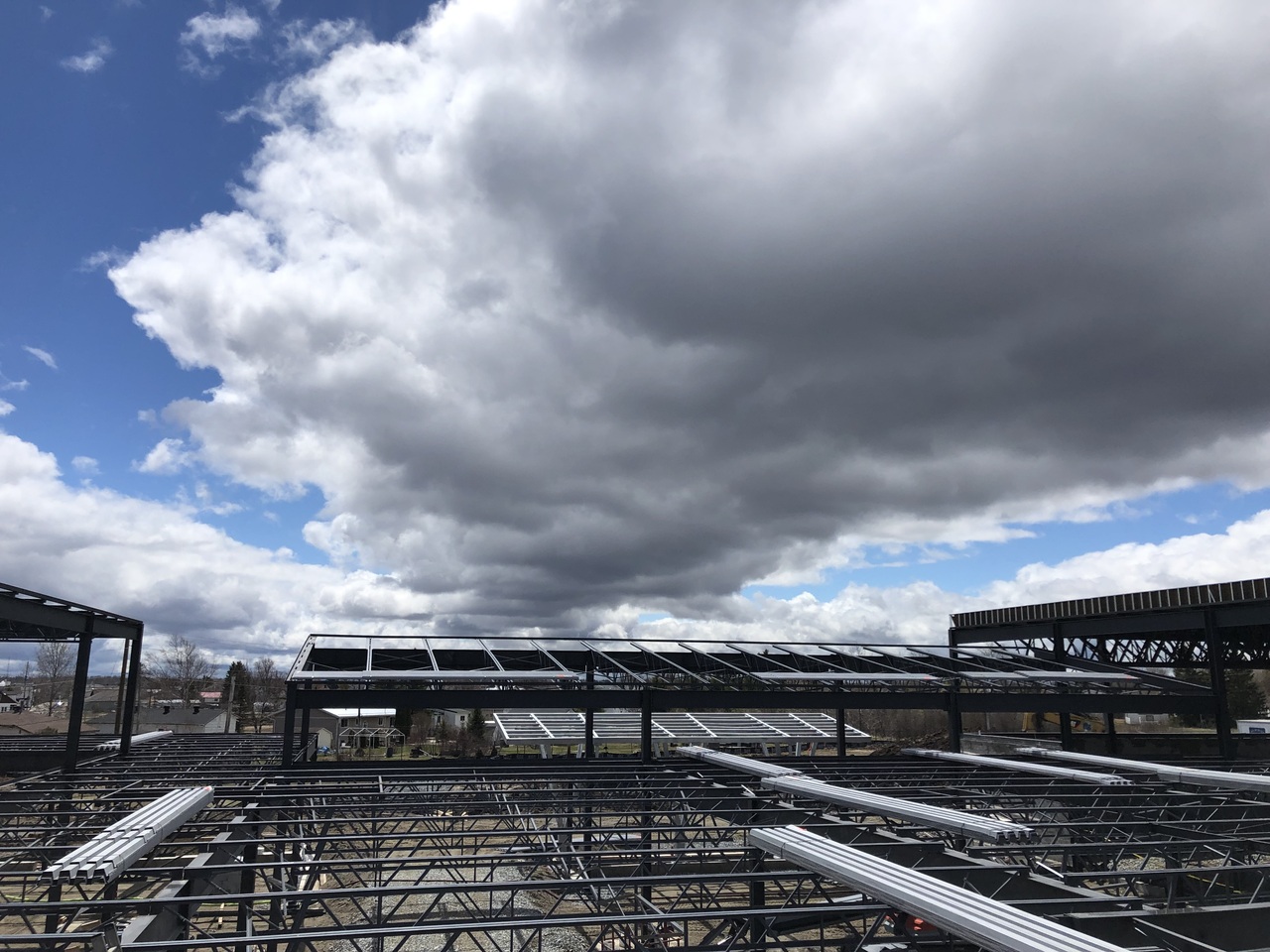 Industrial worker in protective gear welding metal beams, emitting bright sparks in a factory setting.
