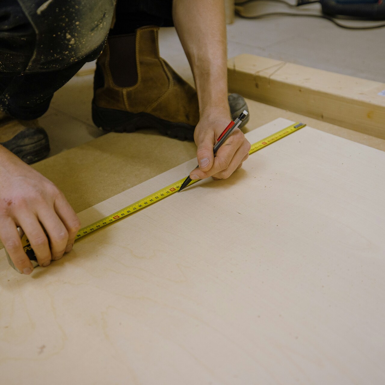 Professional home renovation contractors measuring and taking notes in a bright room with tools and workbench