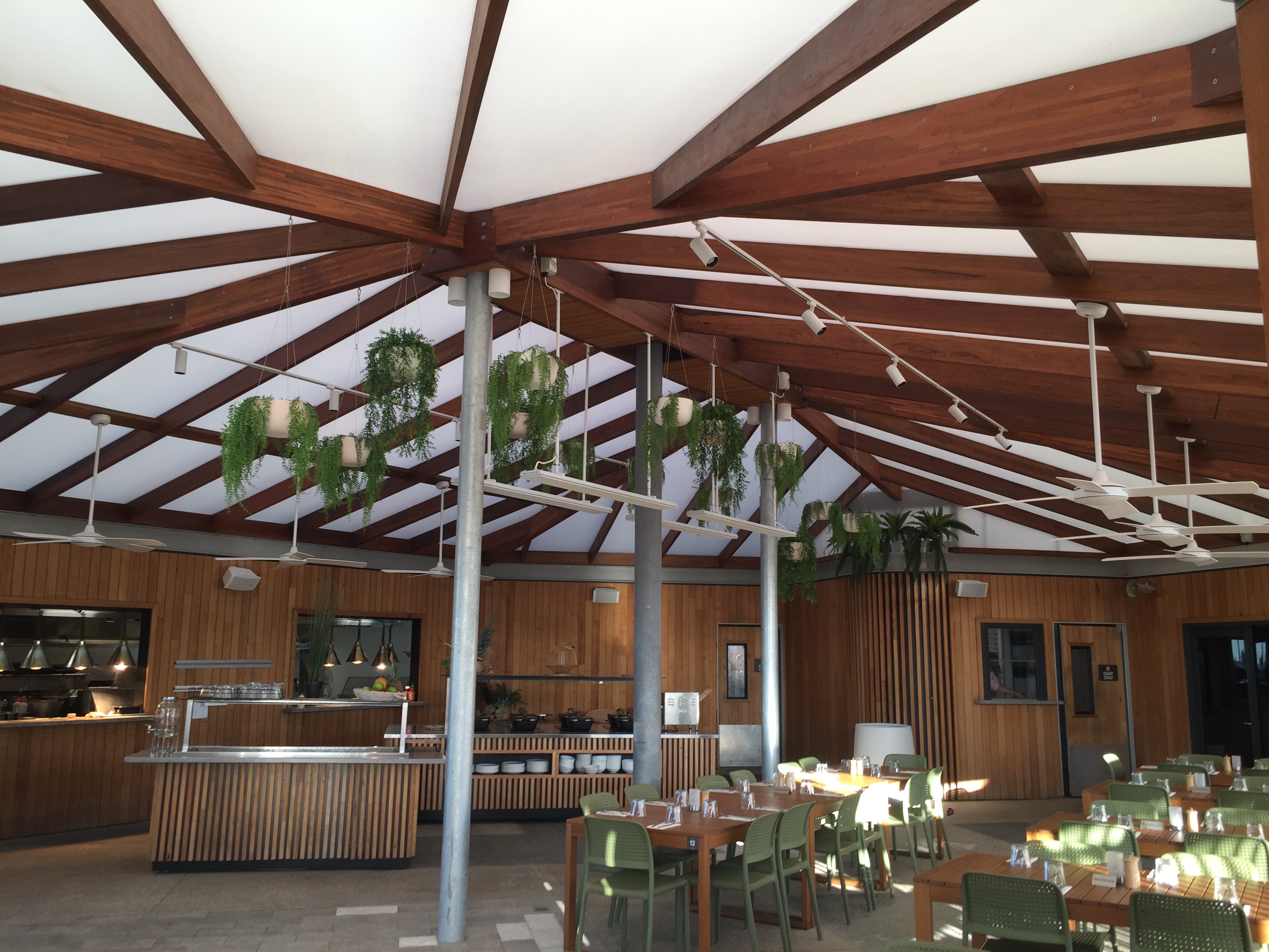 Modern open-plan living room with sleek kitchen, large windows opening to garden, wooden accents, and stylish furniture.